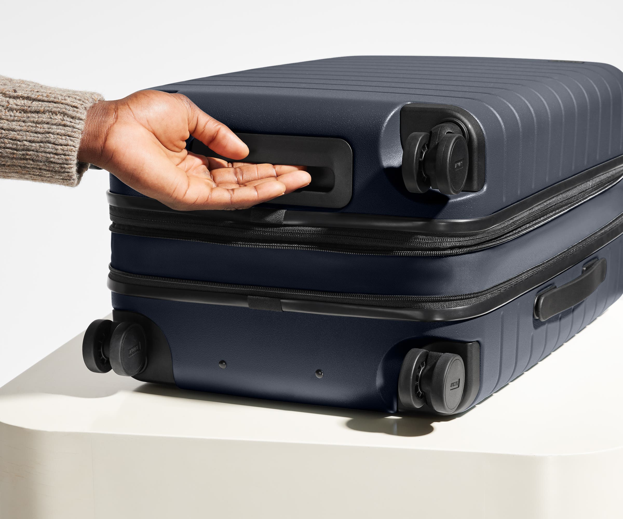 The Carry-On Flex suitcase in Navy Blue shown from below highlighting the underside grab handle