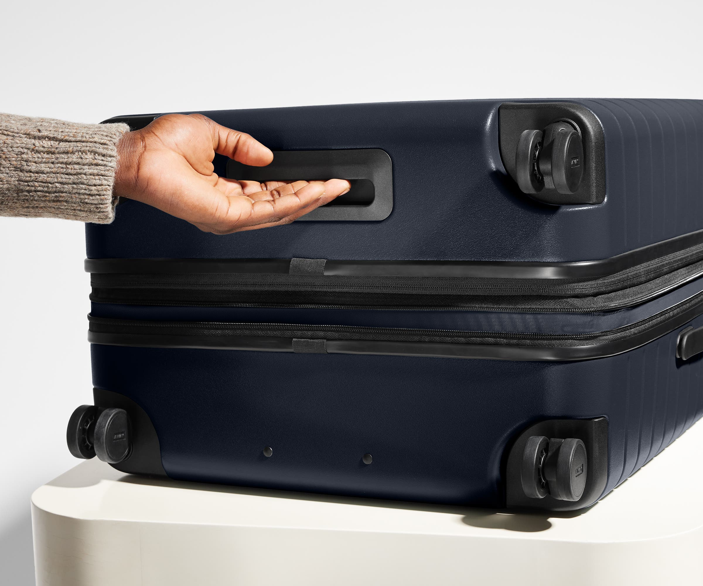 The Large Flex suitcase in Navy Blue shown from below highlighting the underside grab handle