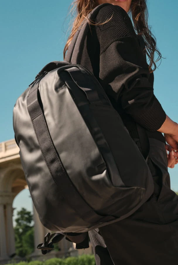 Person wearing a black backpack with a blurred architectural background