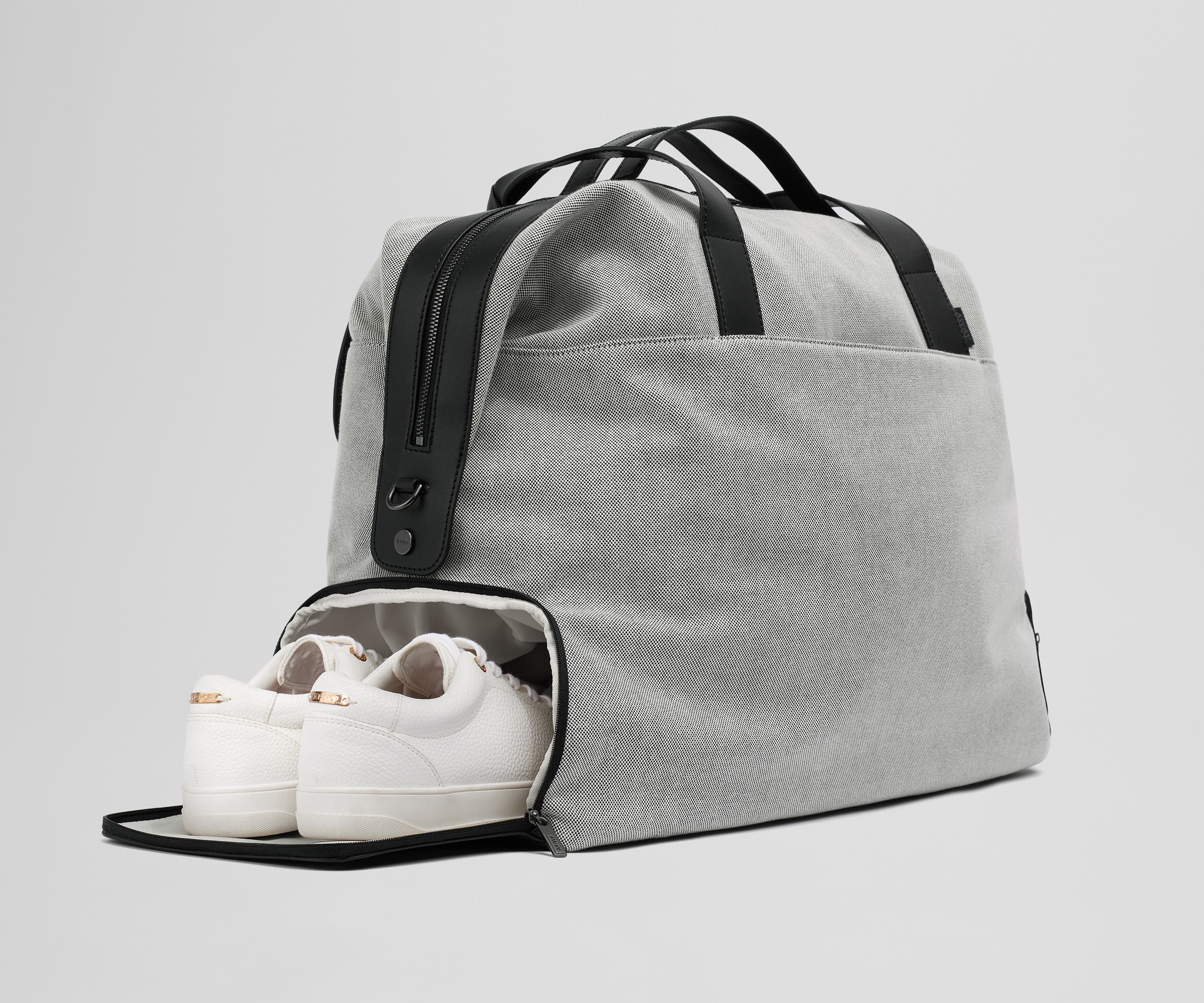 A pair of sneakers in the zippered shoe compartment