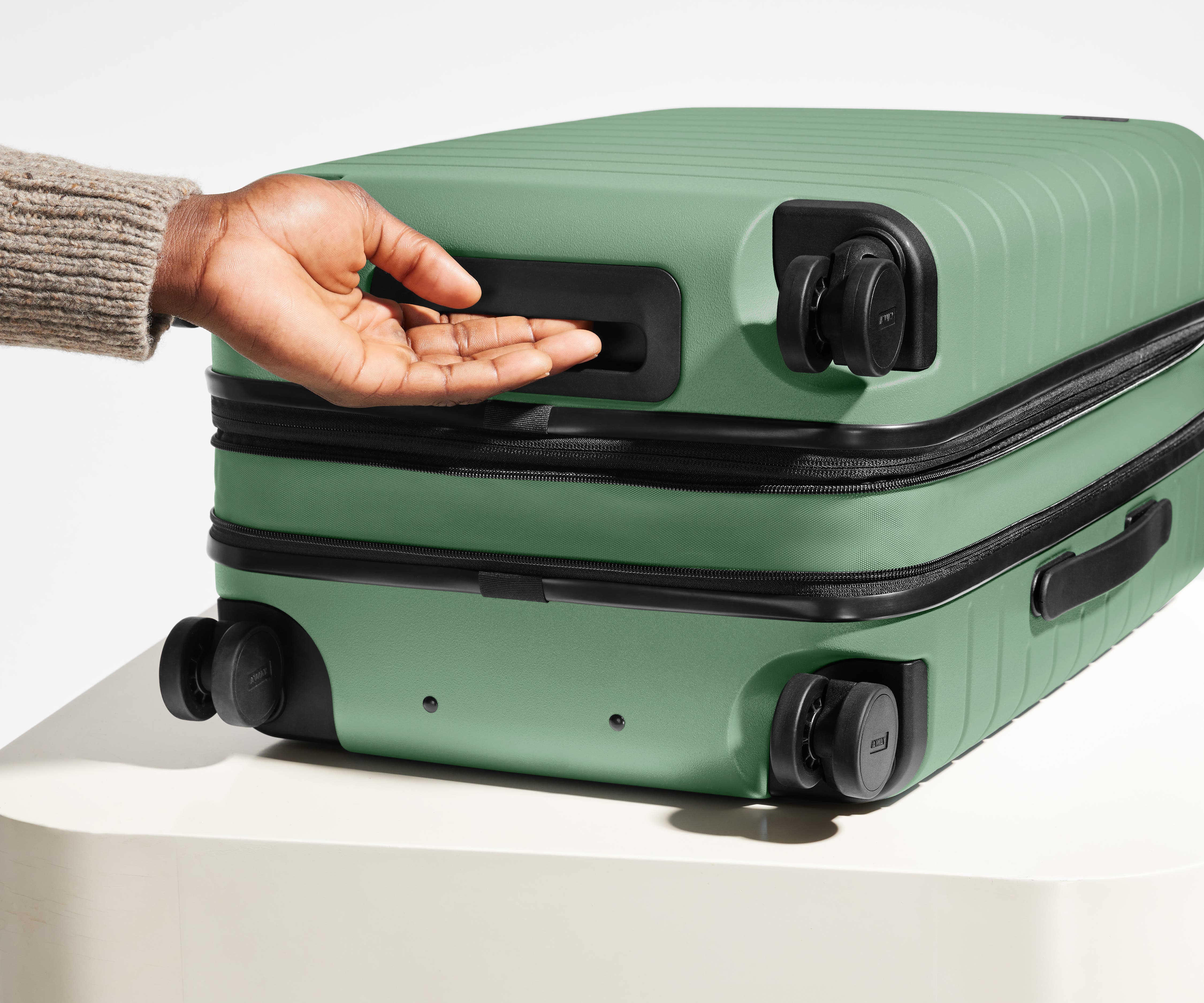 The Bigger Carry-On Flex suitcase in Sea Green shown from below highlighting the underside grab handle