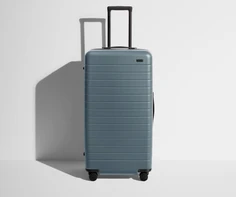 Front product view of The Trunk suitcase in Coast Blue with raised handle