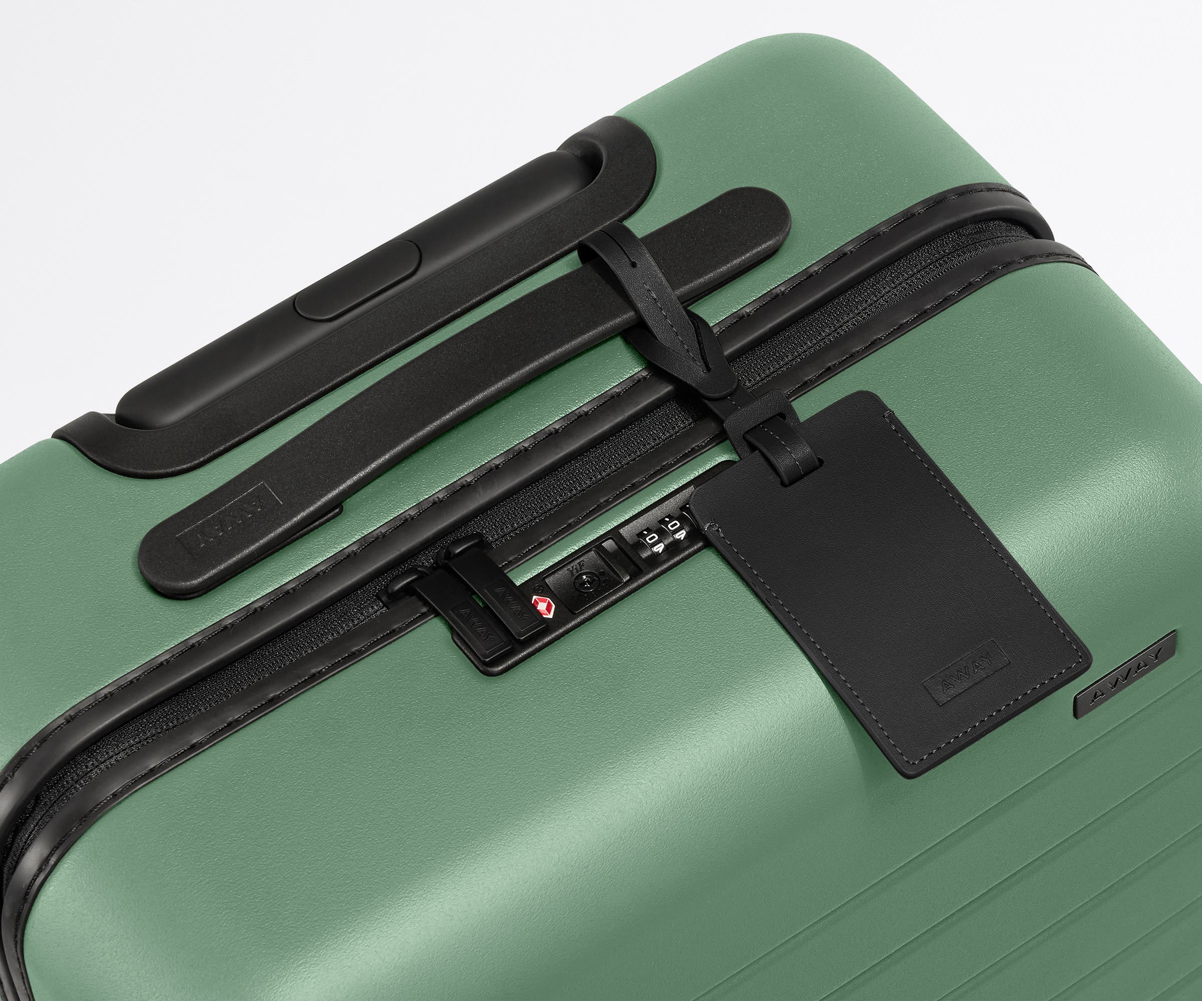 The Carry-On suitcase in Sea Green shown shown from above highlighting TSA-approved combination lock and recycled leather luggage tag