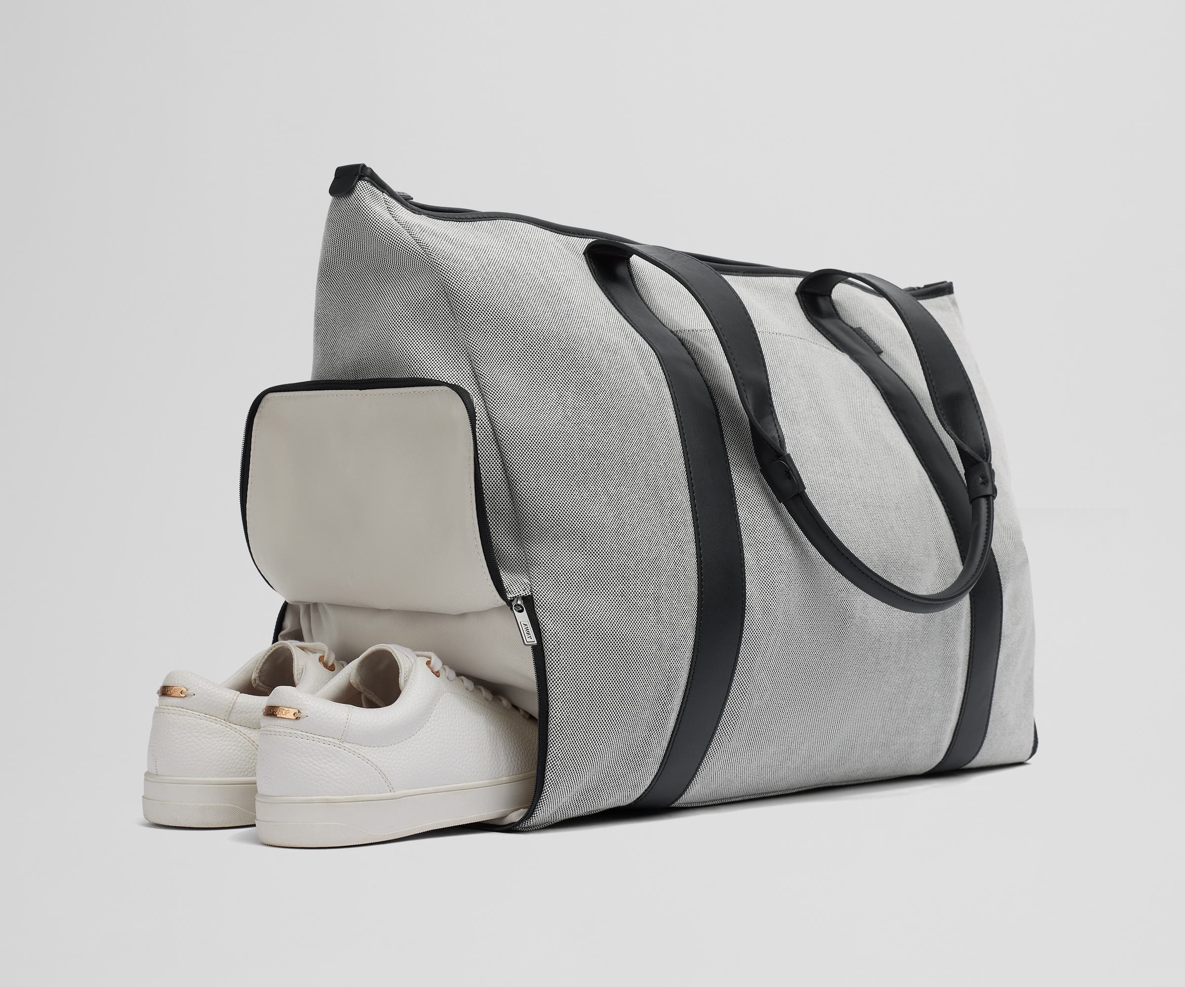 A pair of sneakers in the zippered shoe compartment