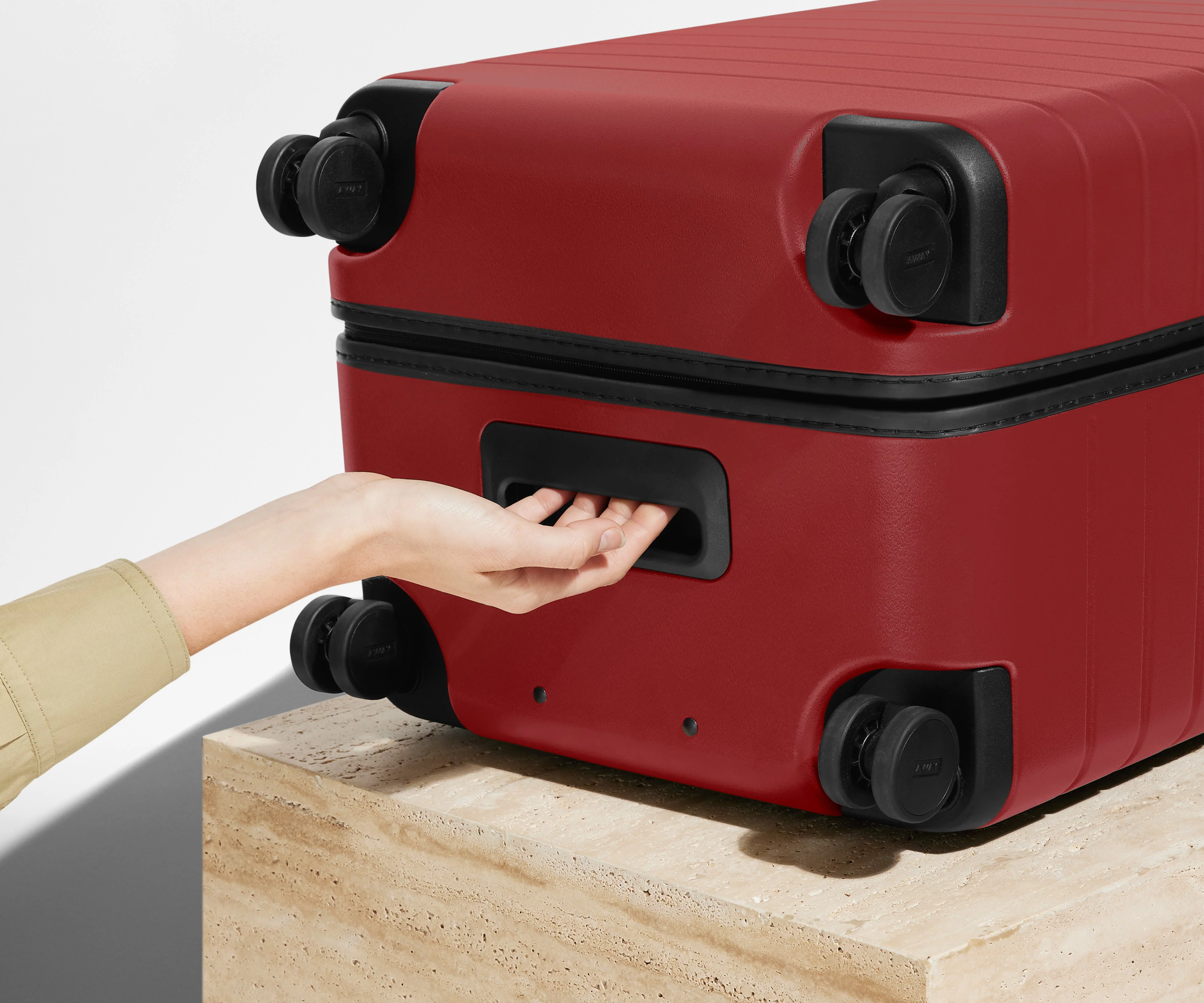 The Trunk suitcase in Tango Red shown from below highlighting the underside grab handle