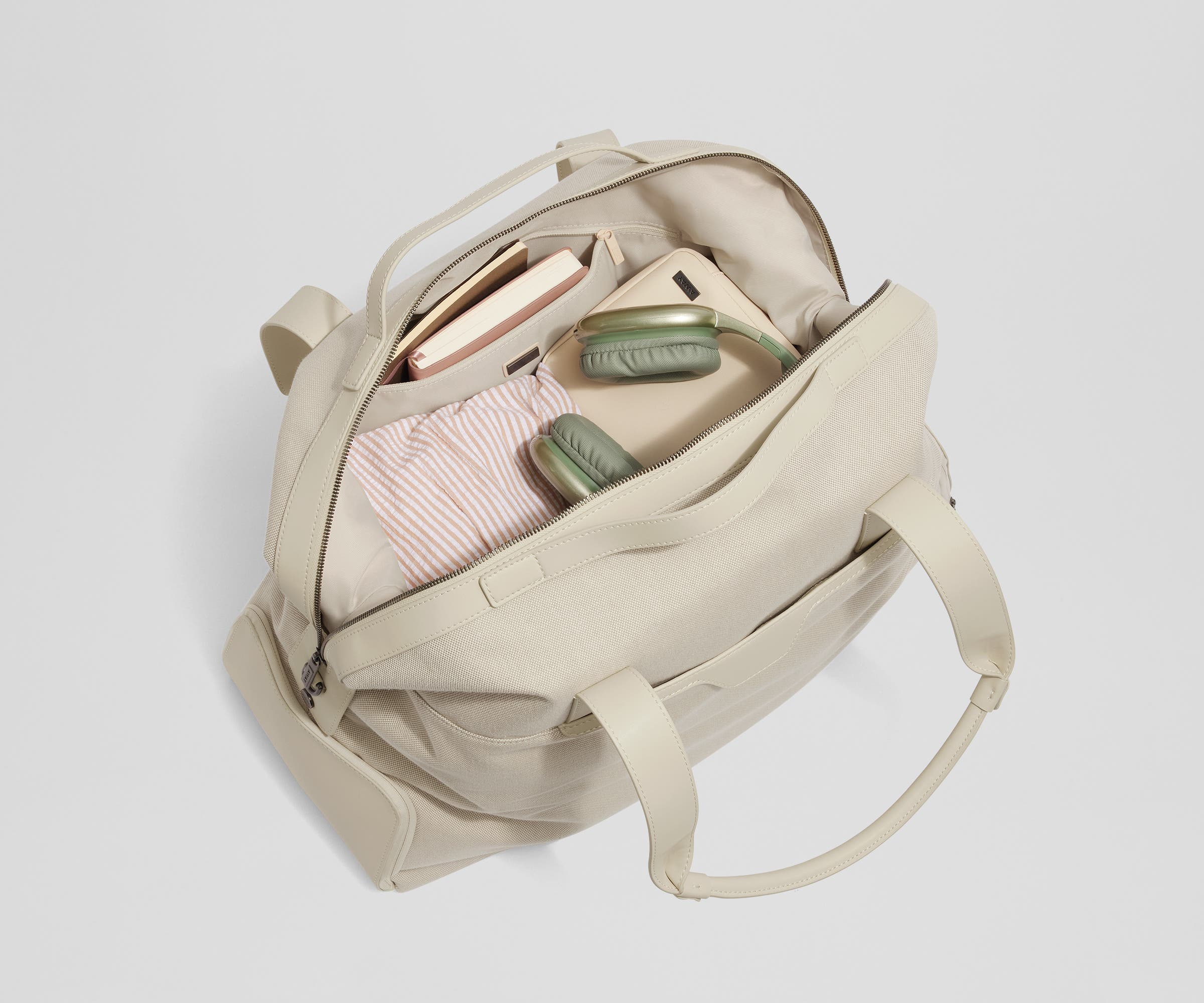 Top-down view of the weekender packed with clothing, headphones, a toiletry bag, and notebook