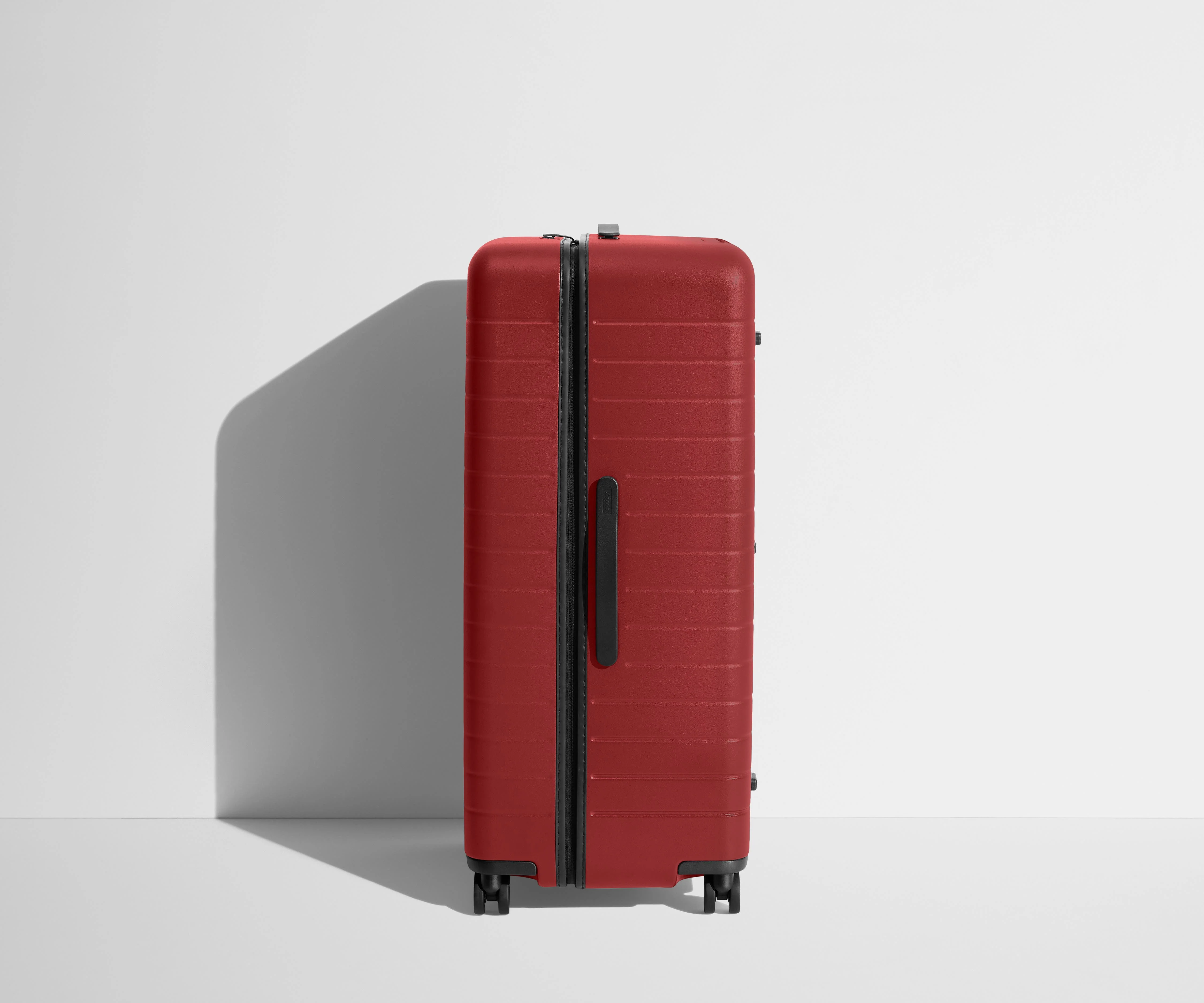 Side product view of The Trunk suitcase in Tango Red to show the slimmer top lid and deeper main compartment for easy access and packing