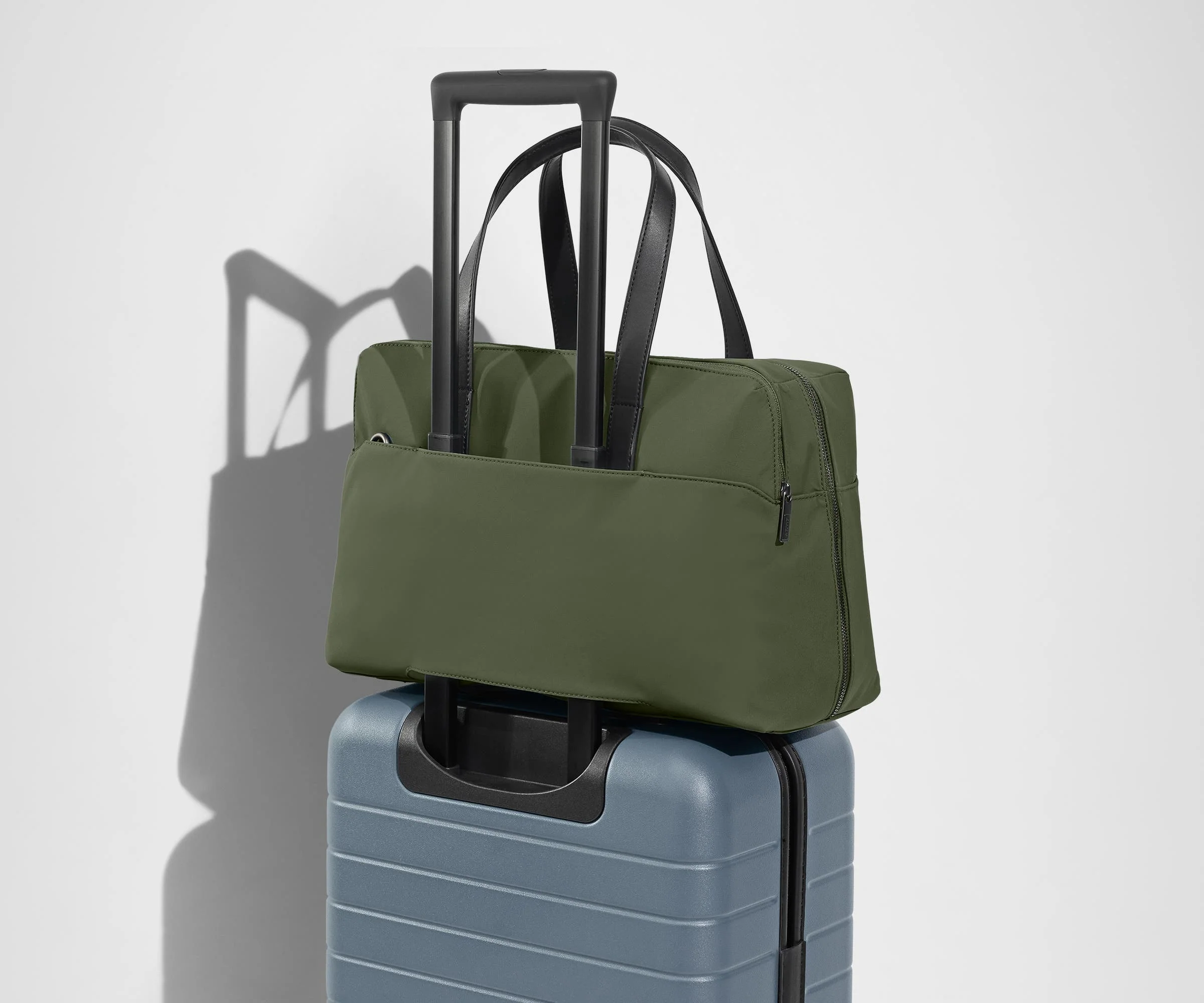 The Everywhere Bag secured to an Away suitcase by its trolley sleeve