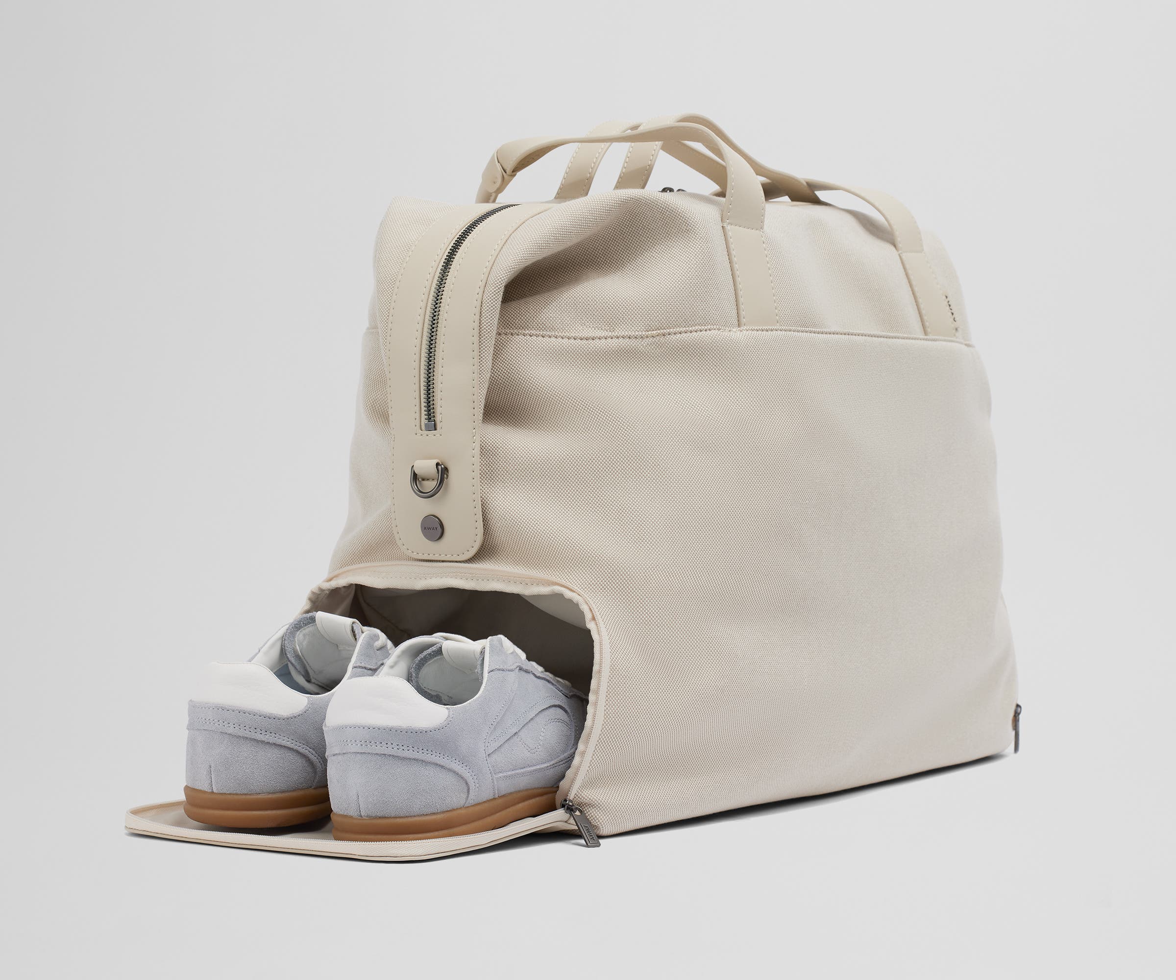 A pair of sneakers in the zippered shoe compartment