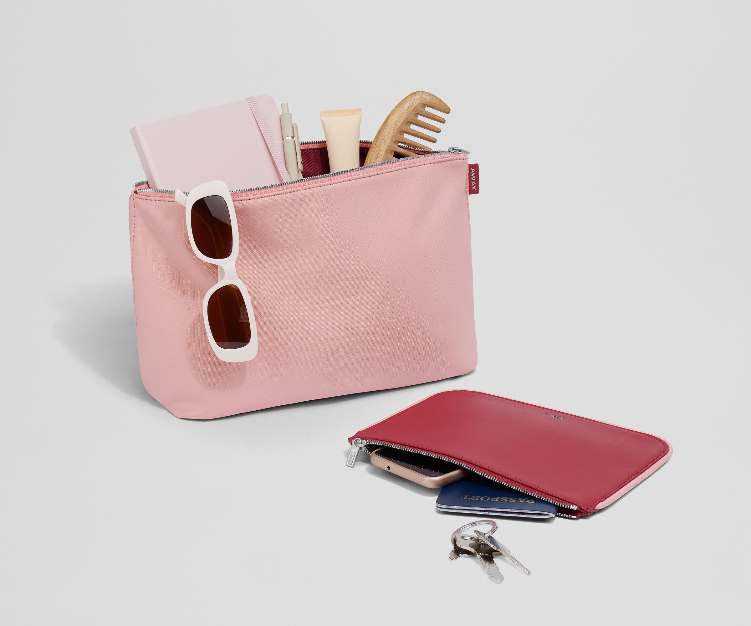 Pouch duo packed with travel essentials like a notebook, passport, keys, and sunglasses