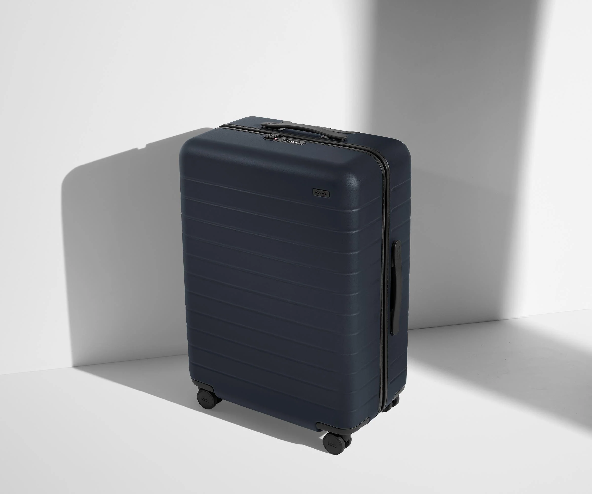 Front product view of The Medium suitcase in Navy Blue with raised handle