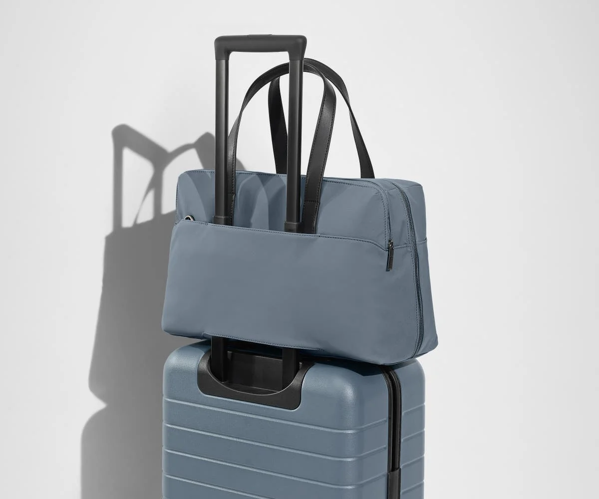 The Everywhere Bag secured to an Away suitcase by its trolley sleeve
