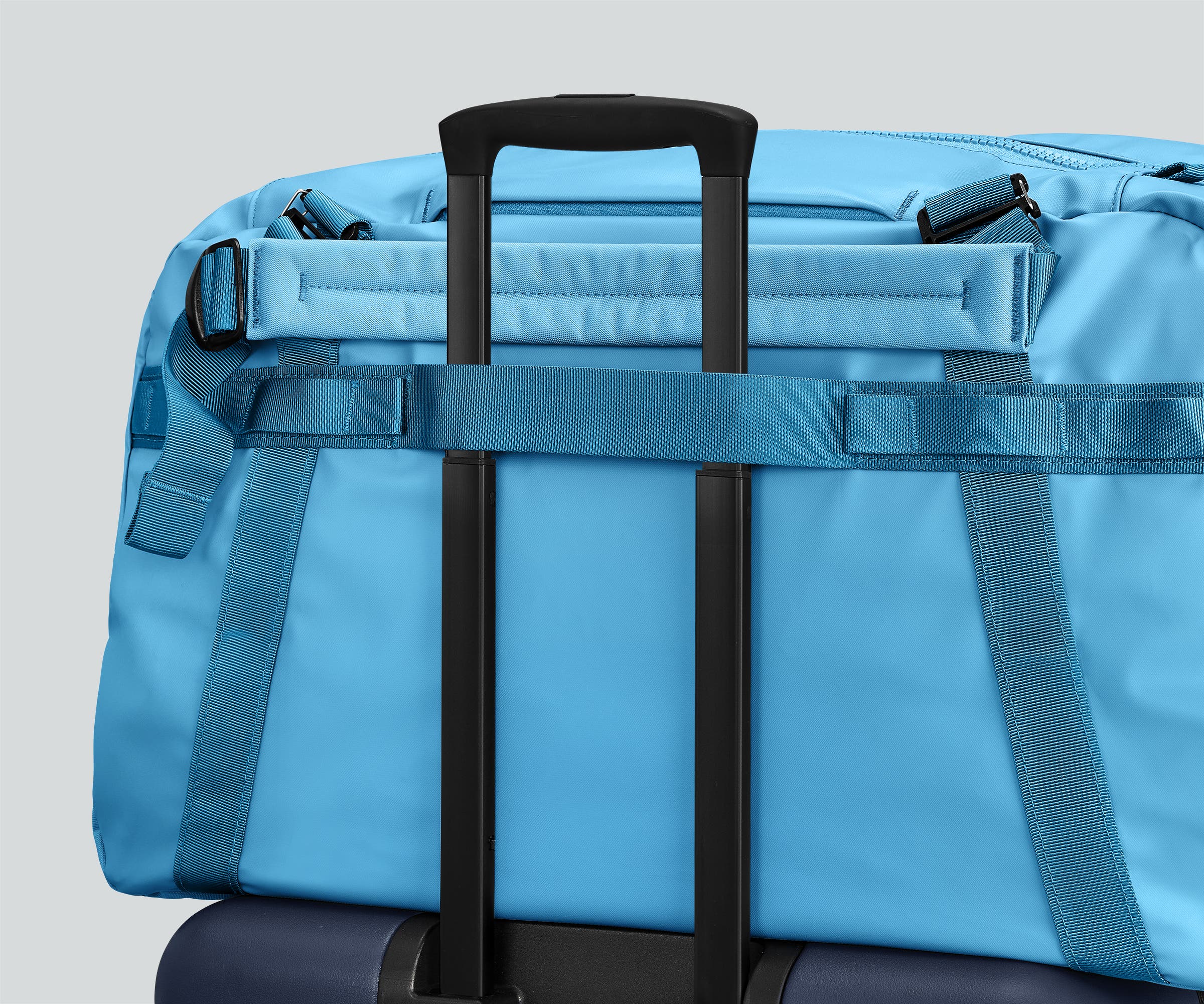 55L duffle bag secured to an Away suitcase by the trolley sleeve