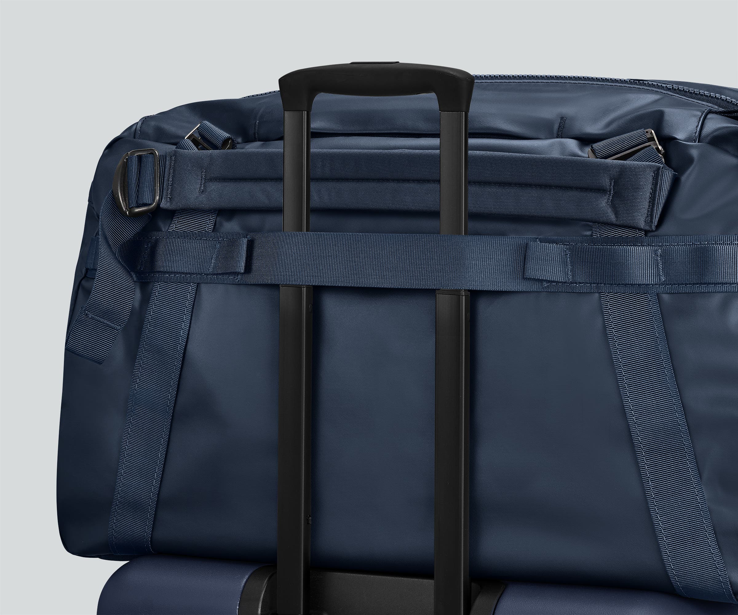 55L duffle bag secured to an Away suitcase by the trolley sleeve