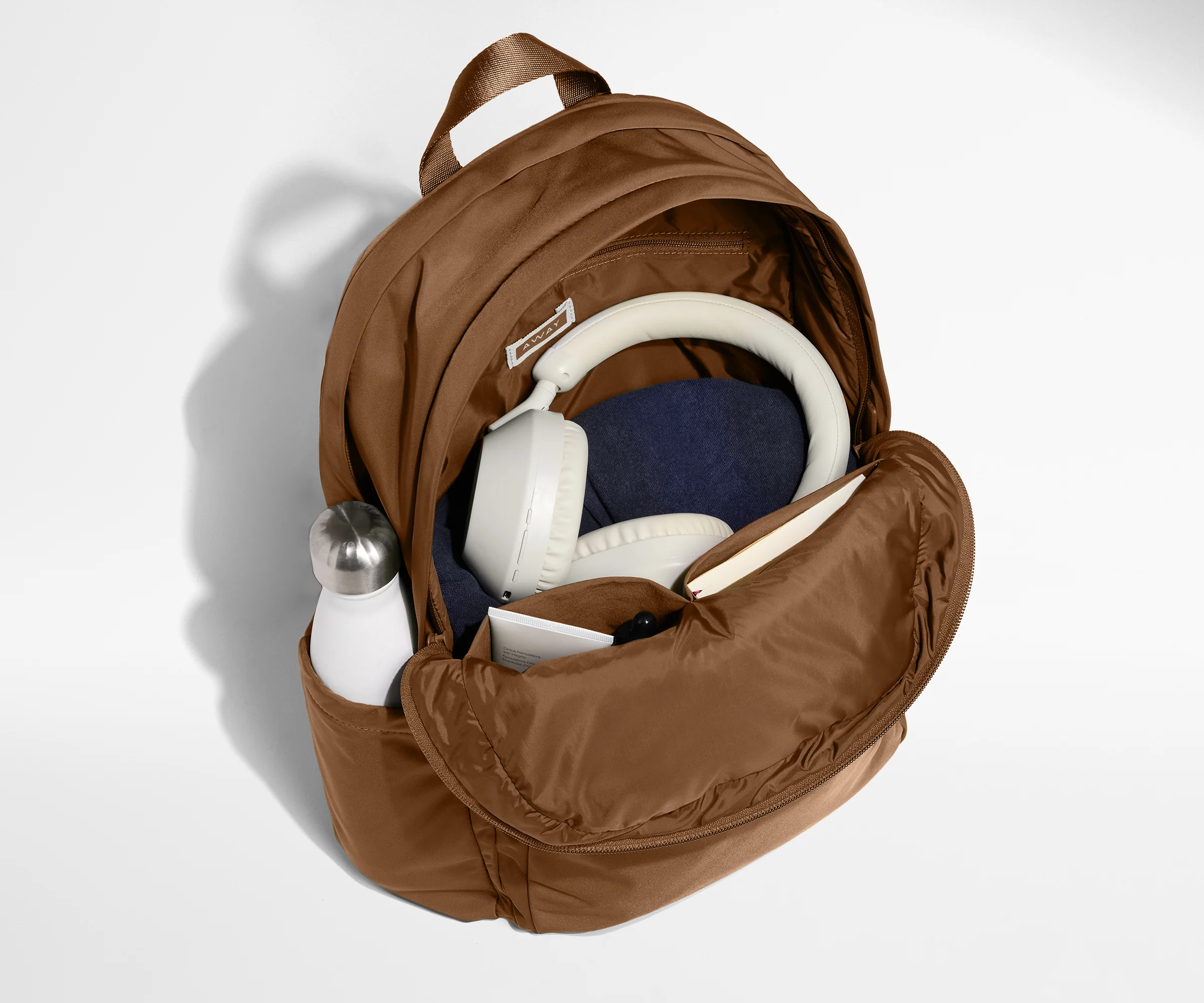 Front compartment packed with a notebooks, headphones, and clothing