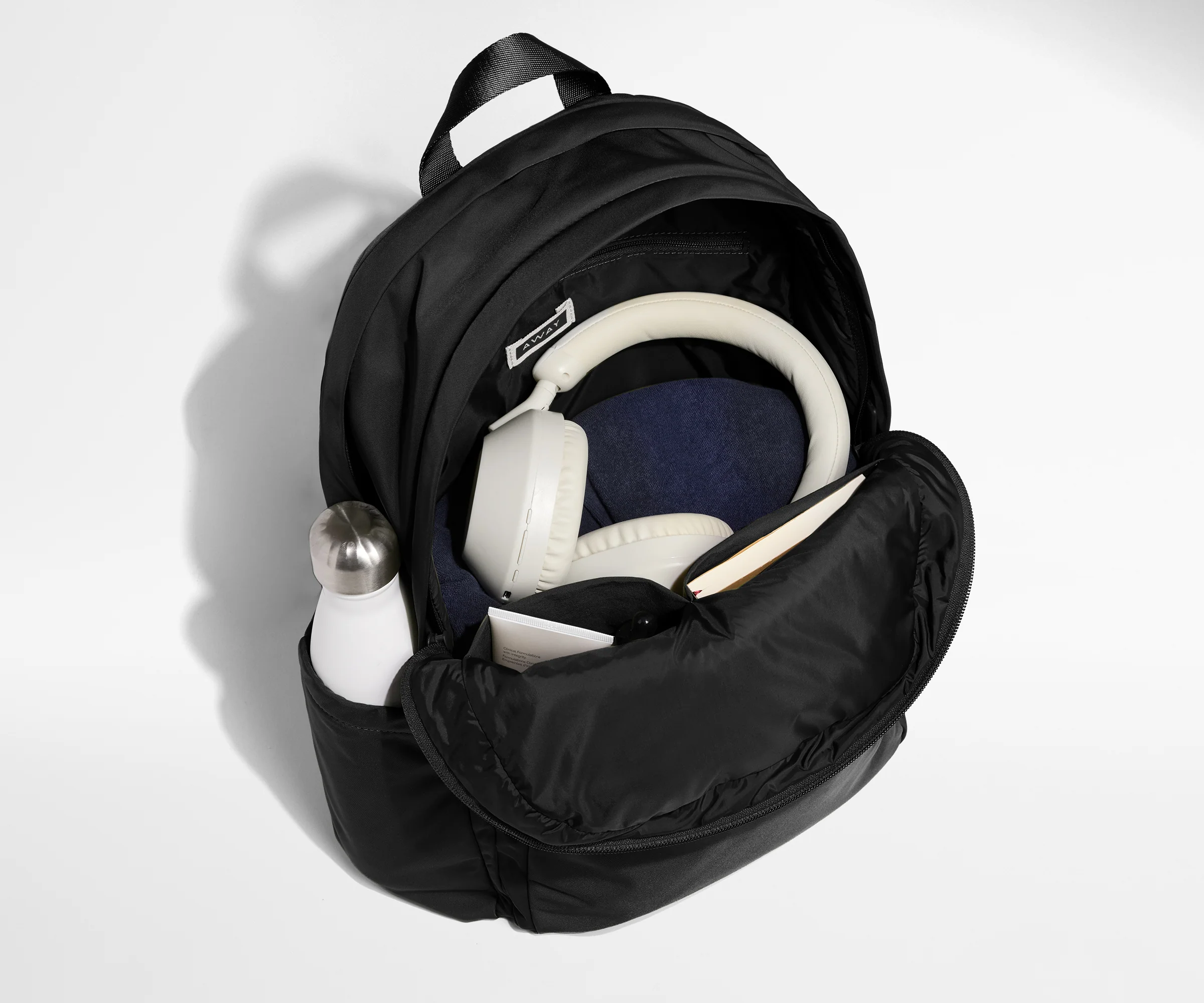 Front compartment packed with a notebooks, headphones, and clothing