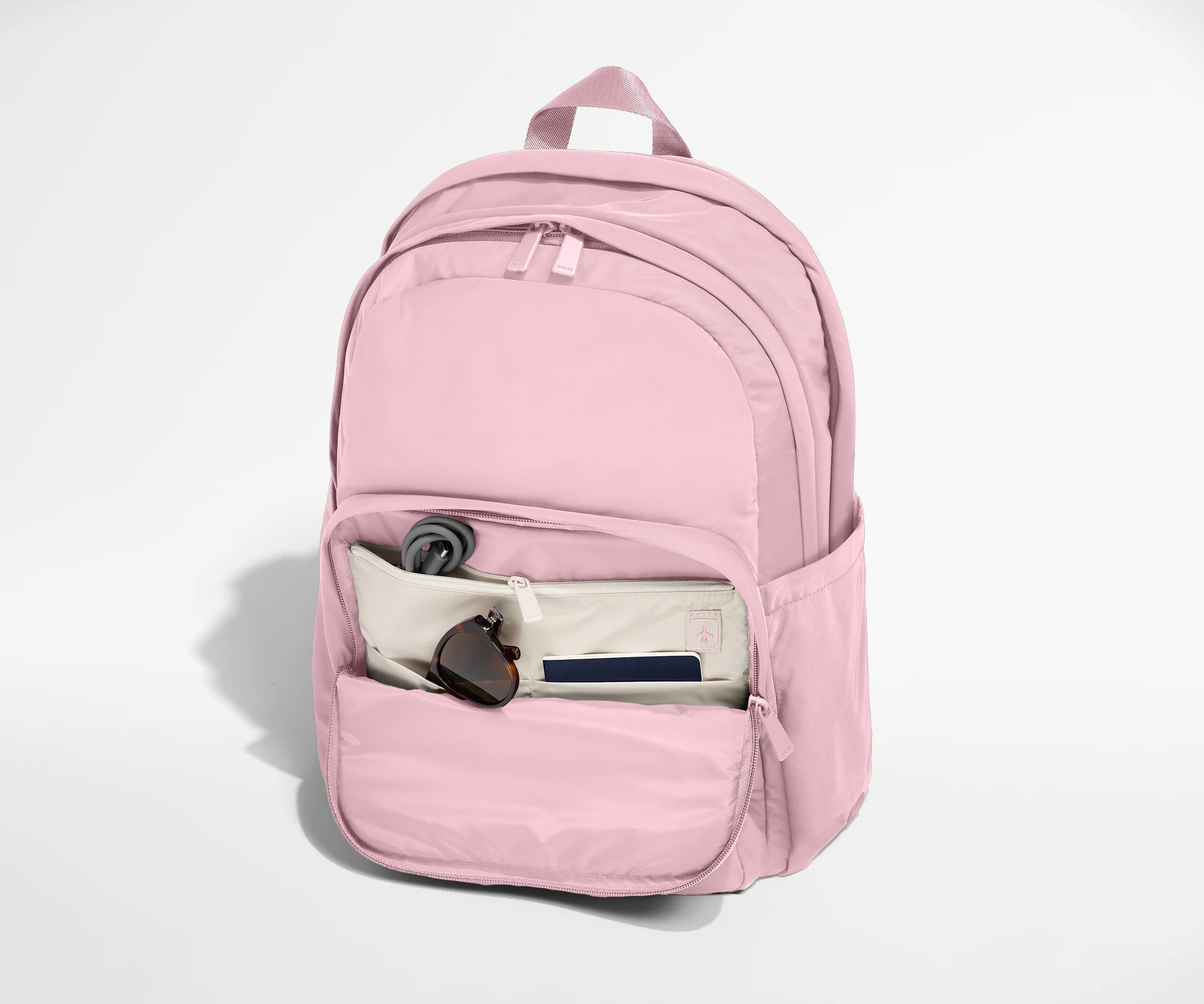 Pink backpack with a pocket open on a white background