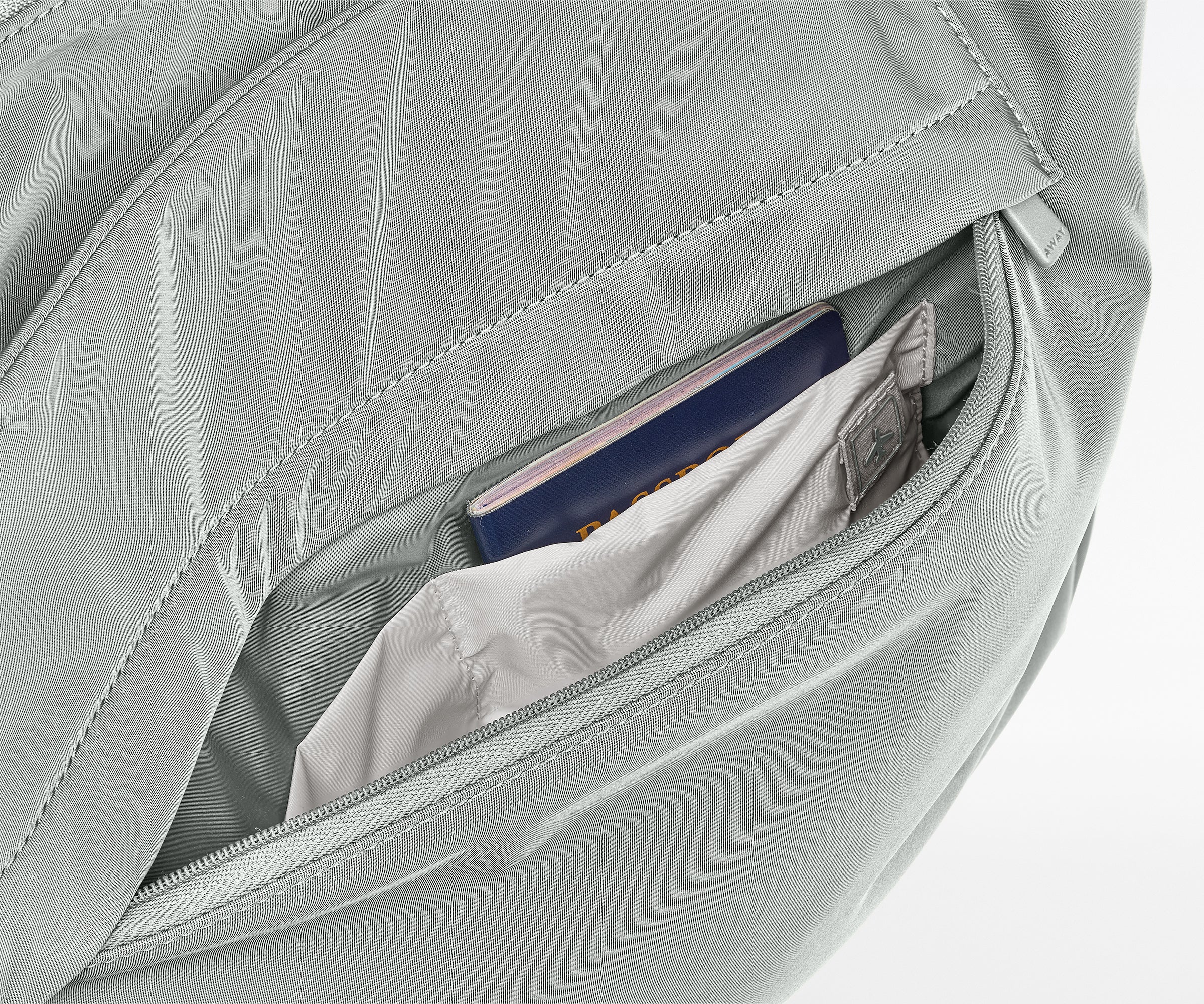 Gray bag with a pocket containing a passport and money on a white background