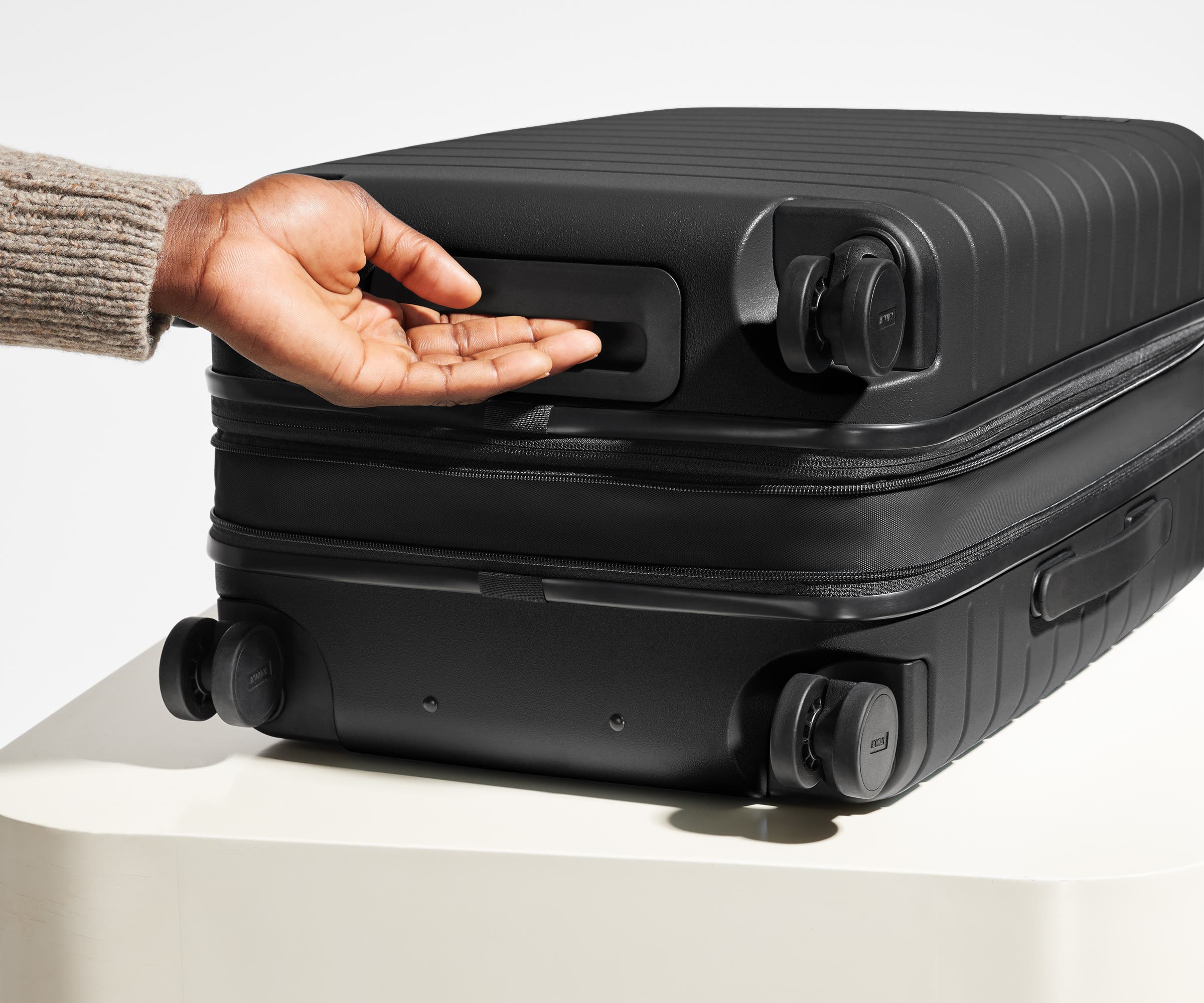 The Carry-On Flex suitcase in Jet Black shown from below highlighting the underside grab handle
