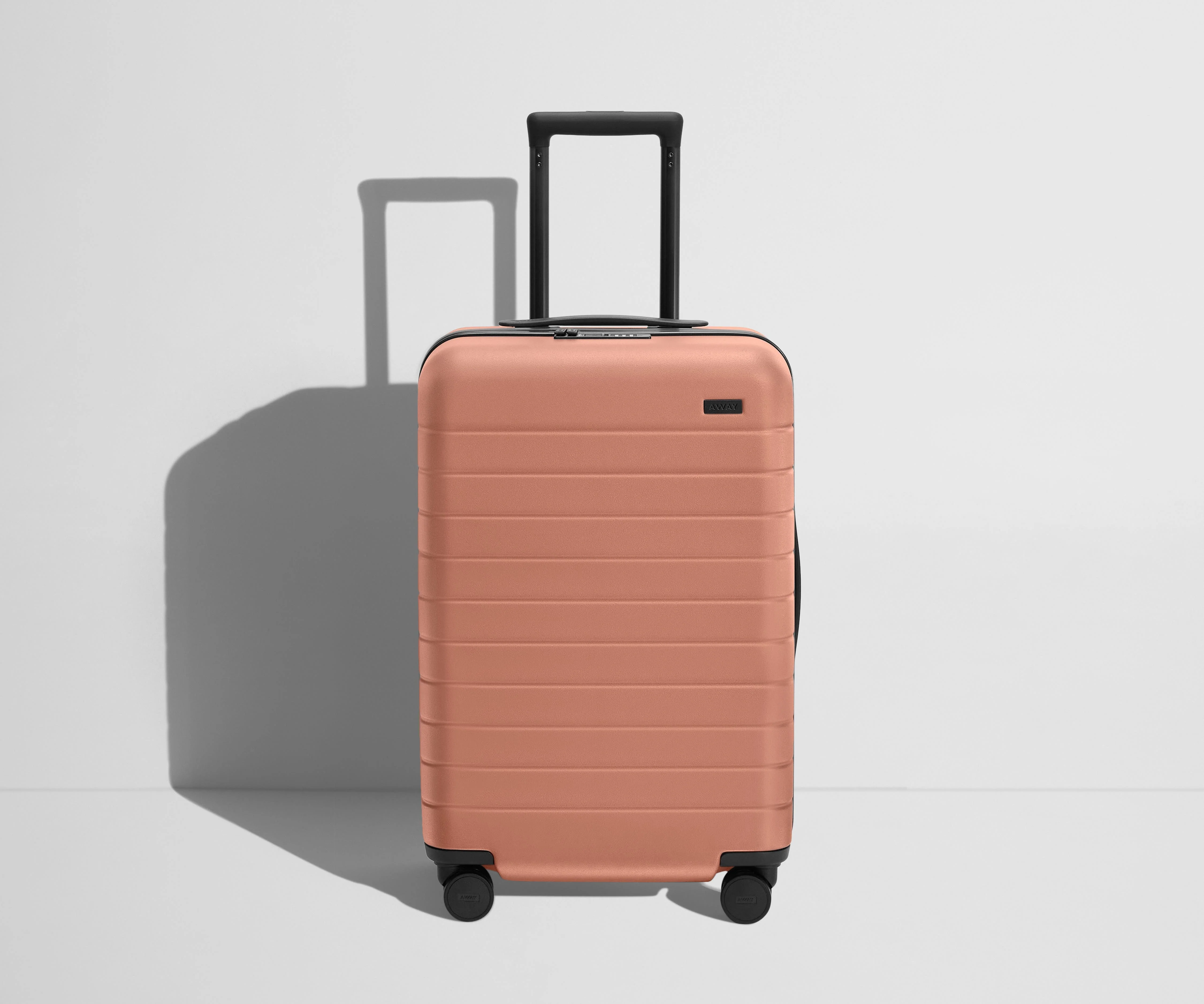 Front product view of The Bigger Carry-On Flex suitcase in Clay Pink with raised handle
