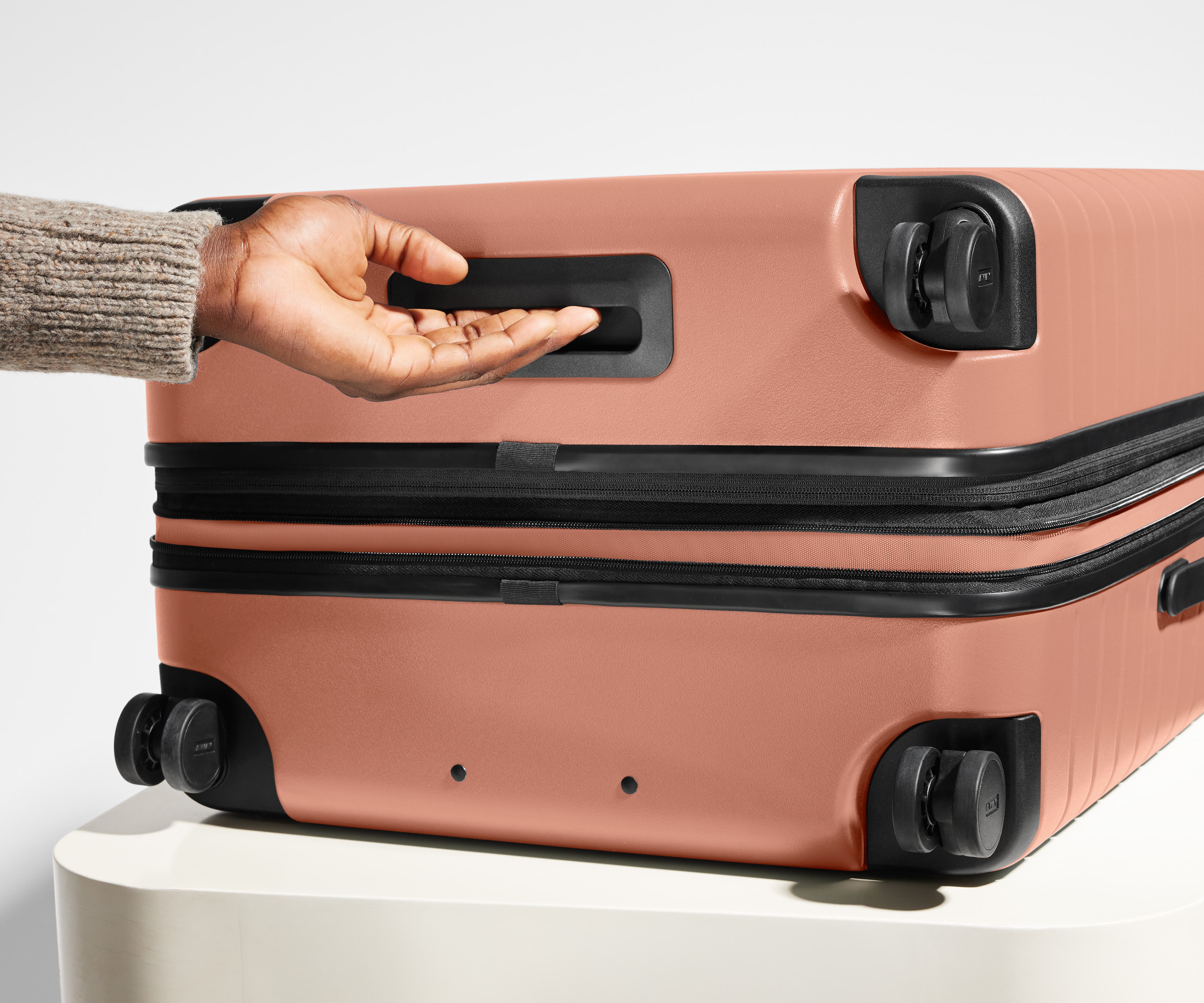 The Large Flex suitcase in Clay Pink shown from below highlighting the underside grab handle