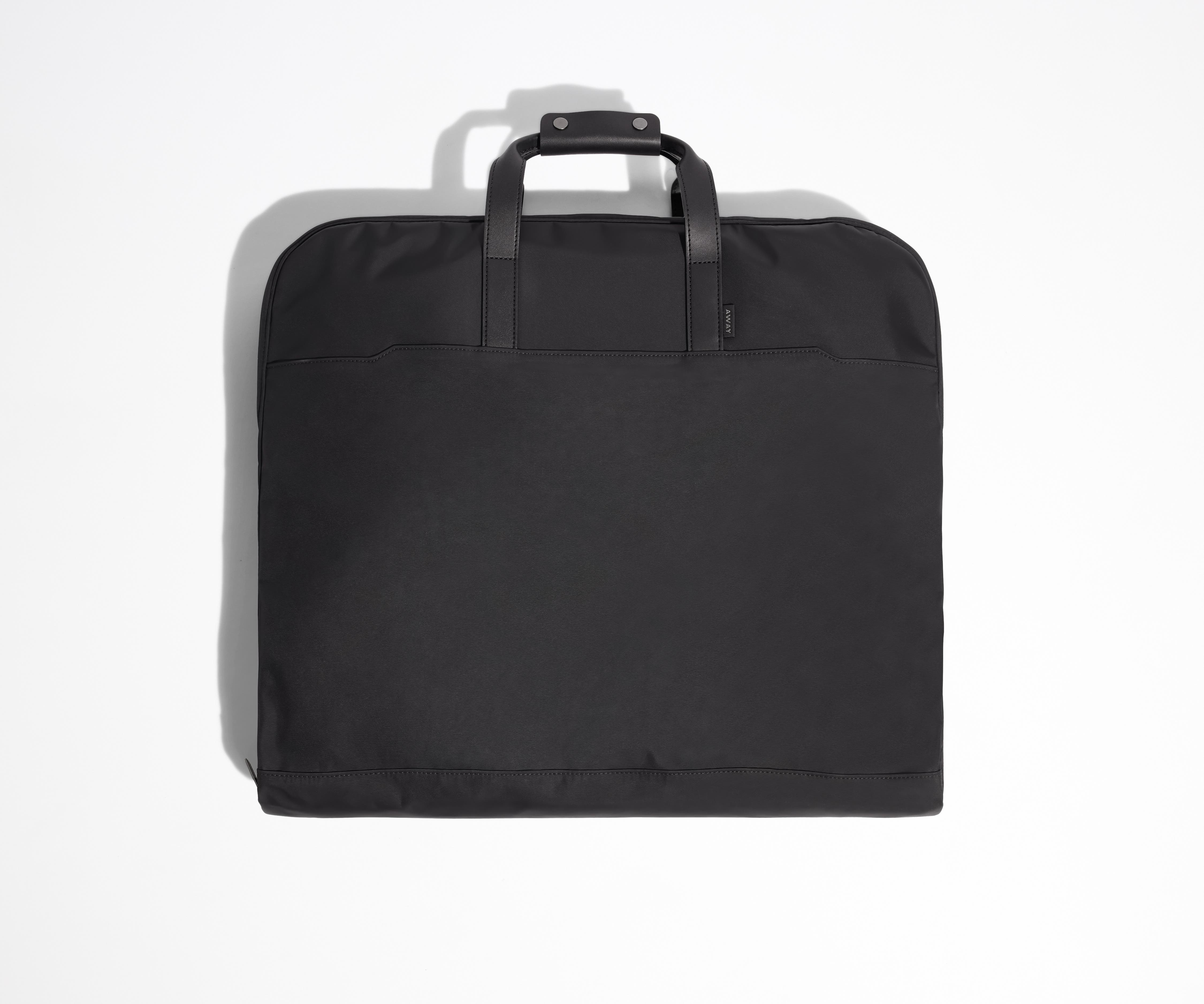 Black garment bag folded view with leather trim handles.
