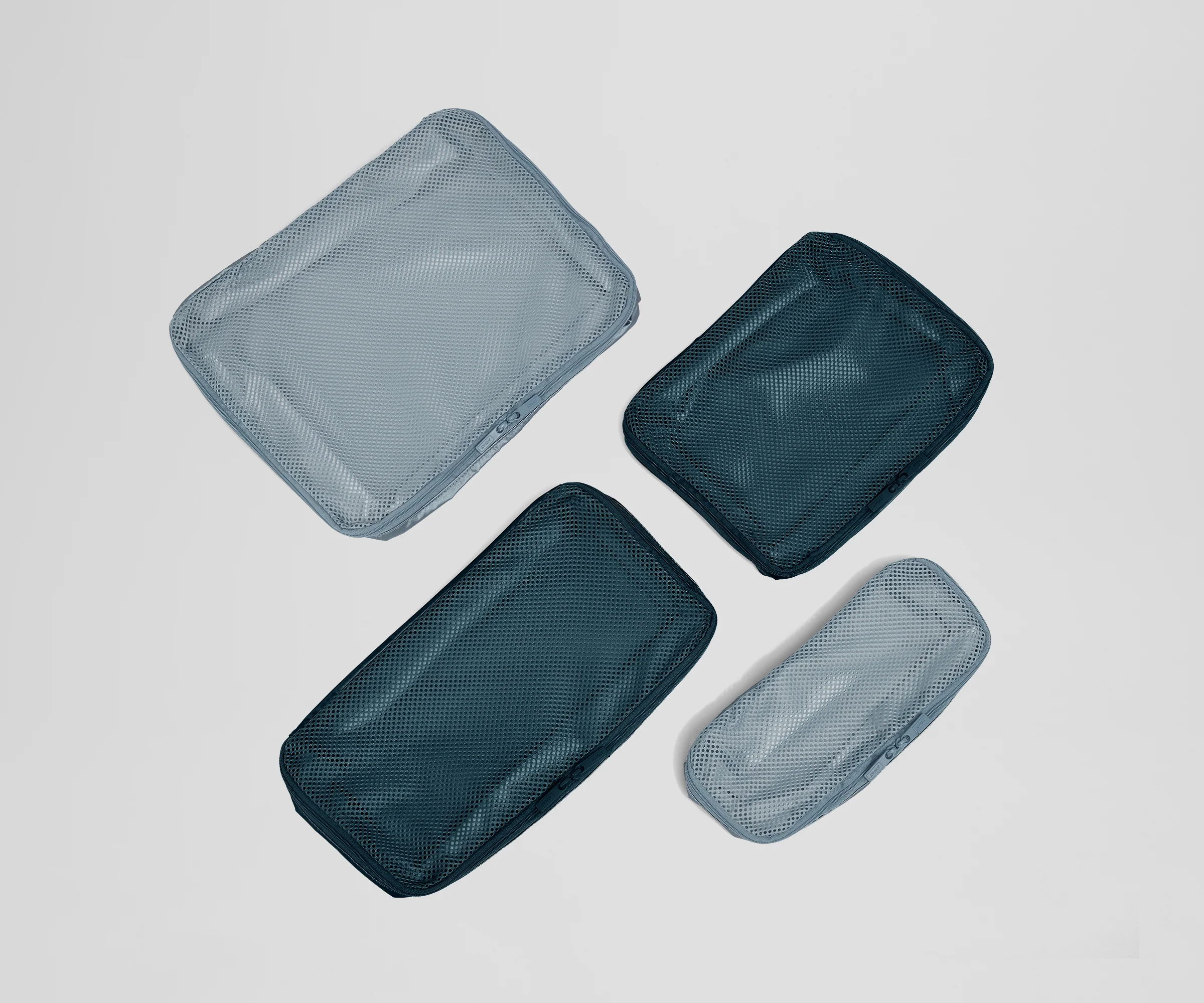 Four mesh packing organizers in different sizes on a light gray background