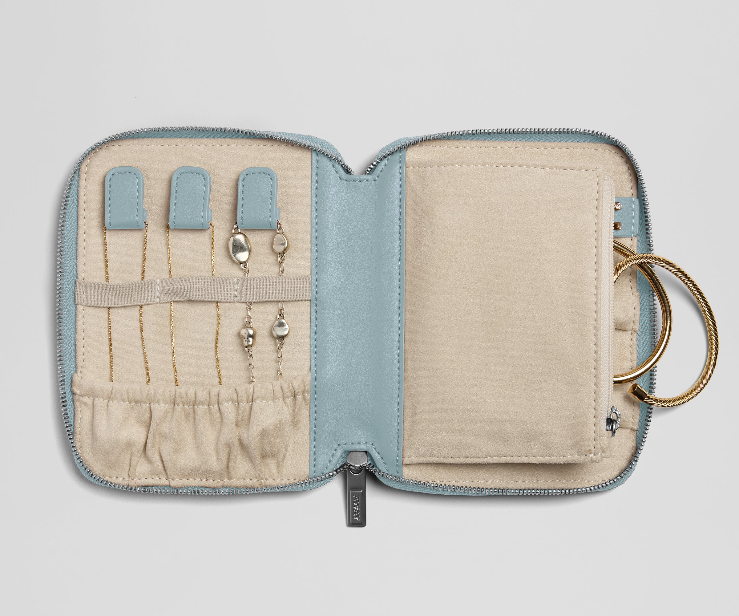 Jewelry case with compartments for earrings and a key, on a light gray background