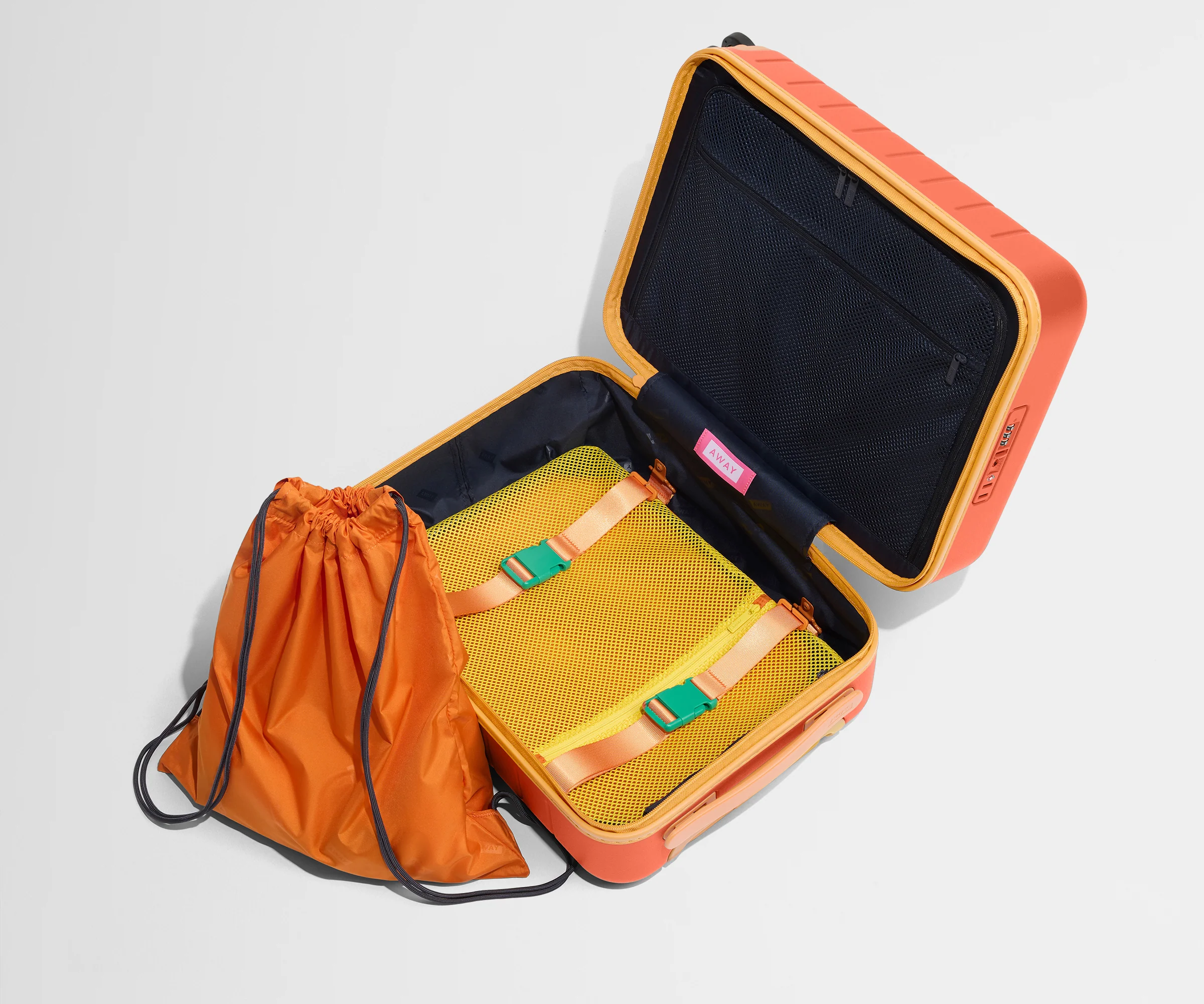 The Kids Carry-On suitcase in Poppy Orange shown open and empty on its side to show capacity, and an orange laundry bag can double as a backpack for smaller travelers.
