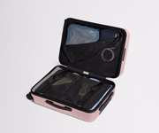 The Bigger Carry-On suitcase in Blush Pink shown open on its side and packed with Away's packing organizers to show capacity and the interior compression system, designed to help you pack more in