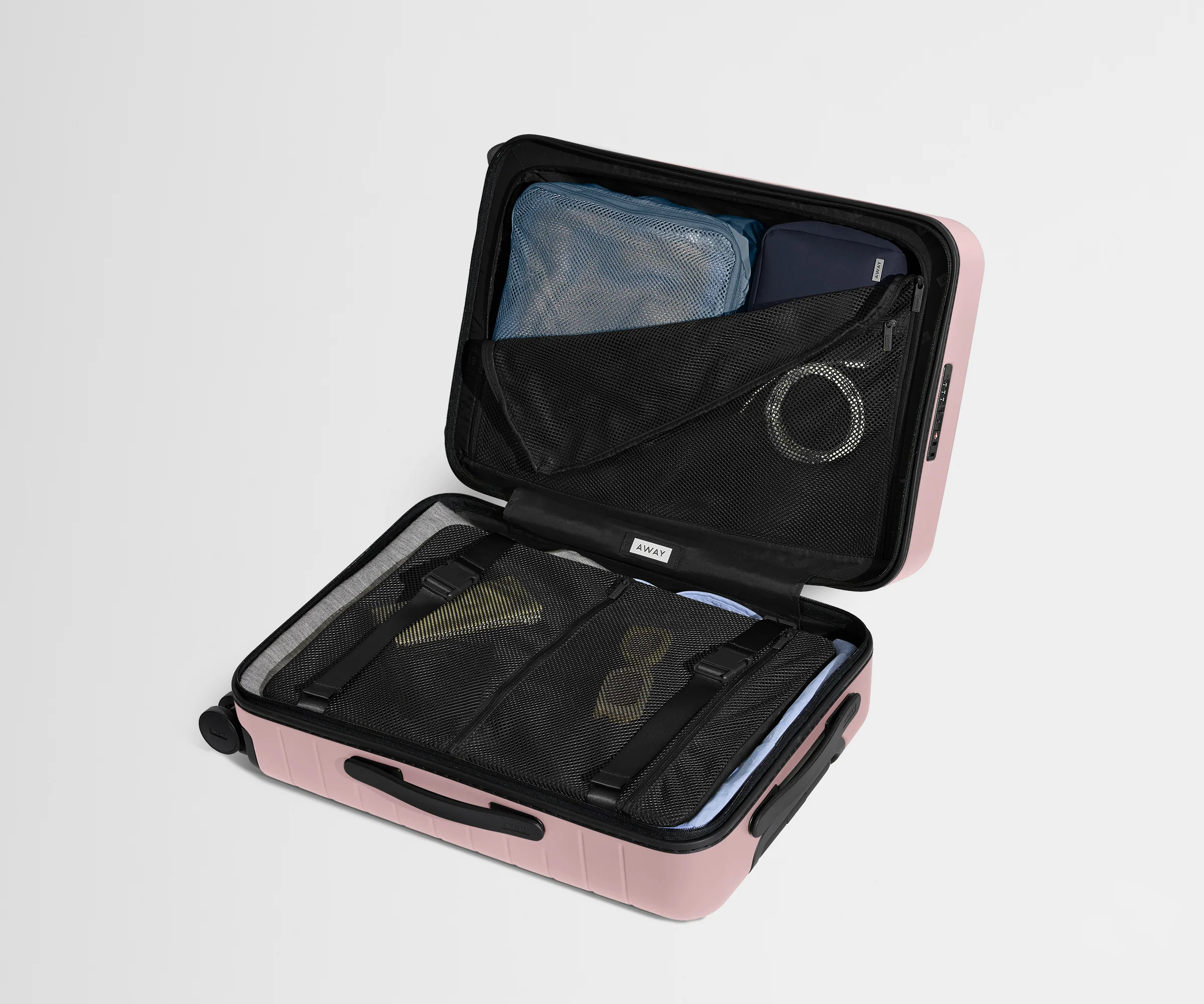 The Bigger Carry-On suitcase in Blush Pink shown open on its side and packed with Away's packing organizers to show capacity and the interior compression system, designed to help you pack more in