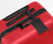 Red suitcase with black handle and tag on a white background