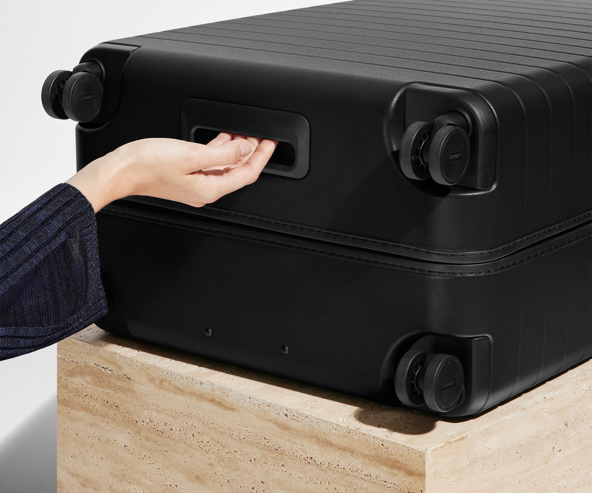 The Medium suitcase in Jet Black shown from below highlighting the underside grab handle
