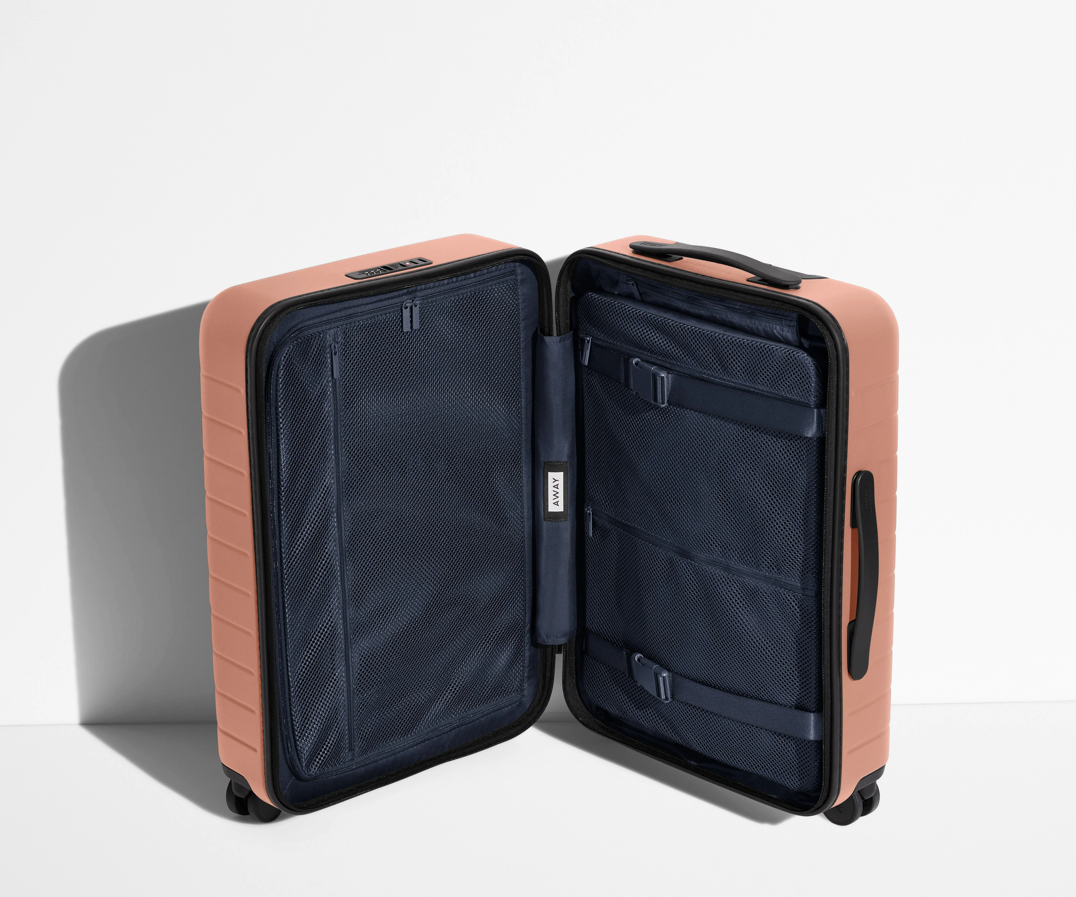 The Bigger Carry-On suitcase in Clay Pink shown open in an upright position to show interior organization and compression system