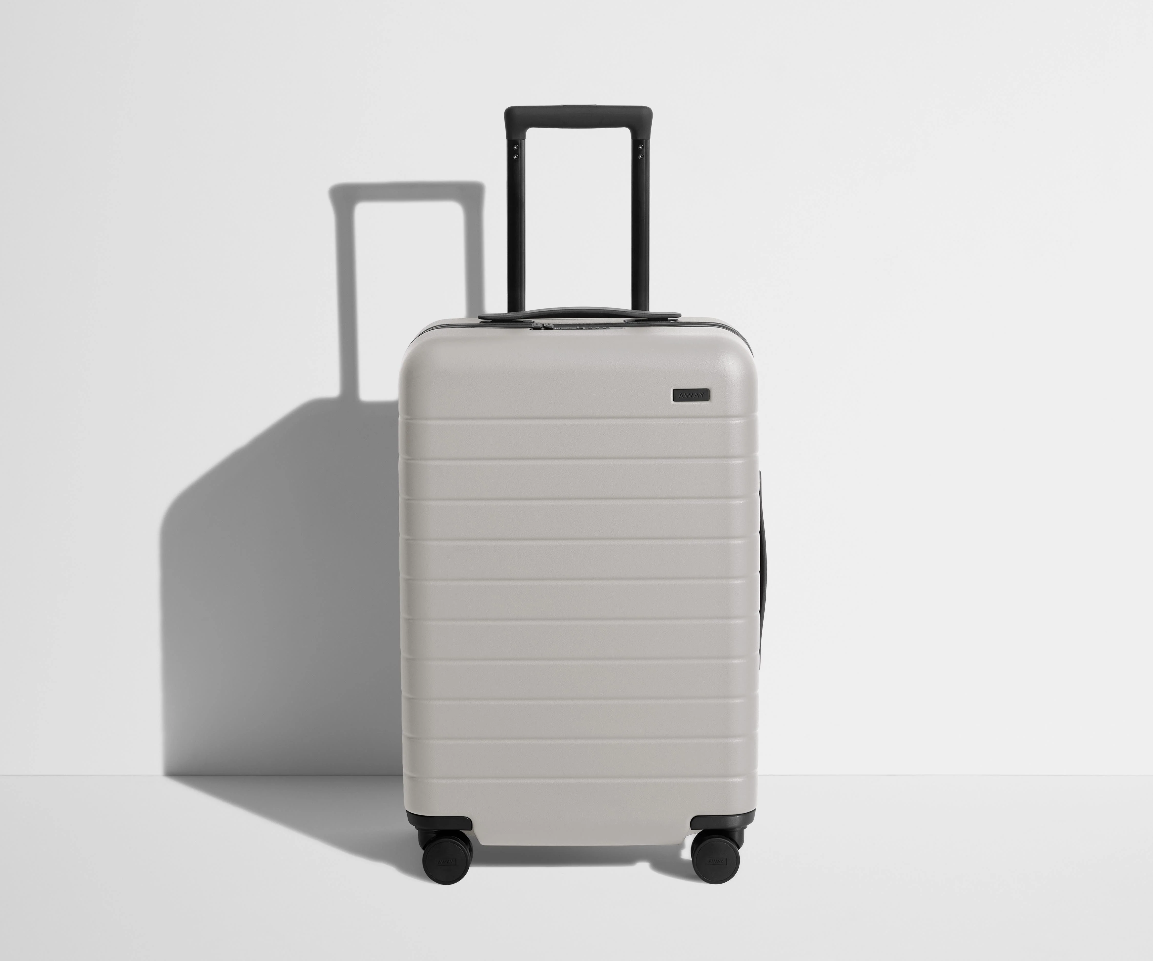 Front product view of The Bigger Carry-On suitcase in Cloud Gray with raised handle