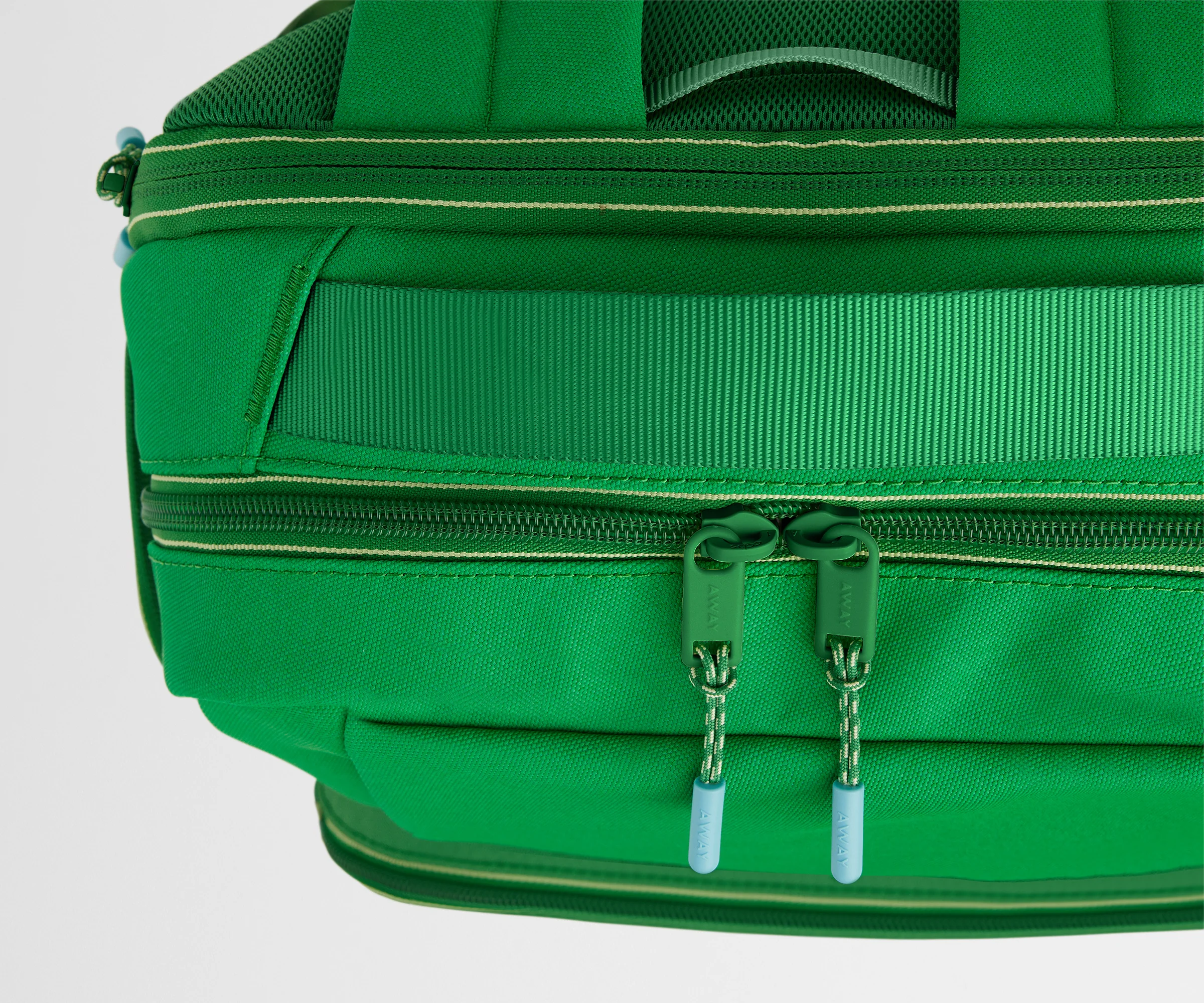 Close-up of a green bag with zippers on a light gray background