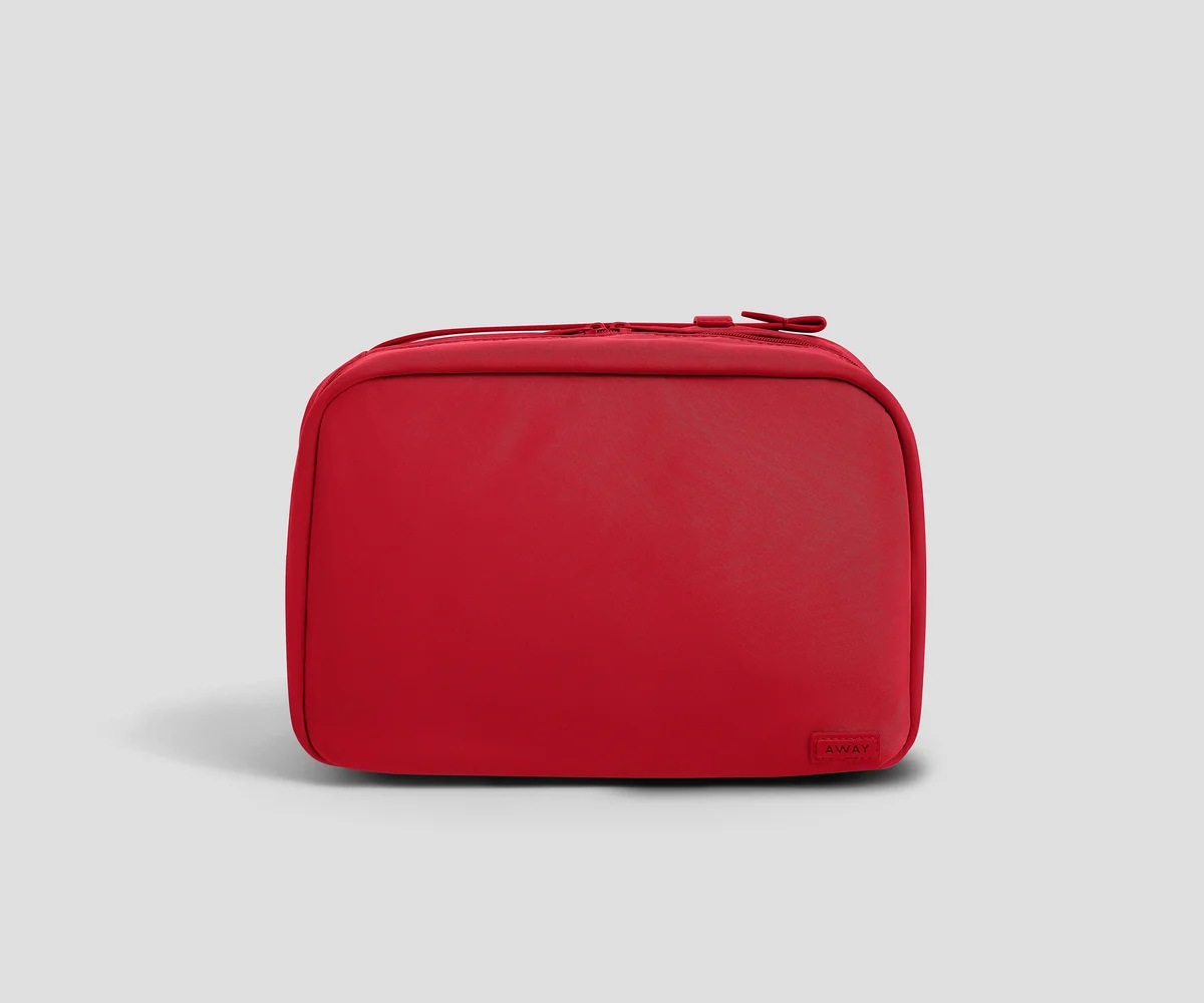 A red zippered toiletry bag with rounded corners, shown from the front on a light gray background.