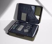 The Large suitcase in Olive Green shown open on its side and packed with Away's packing organizers to show capacity and the interior compression system, designed to help you pack more in