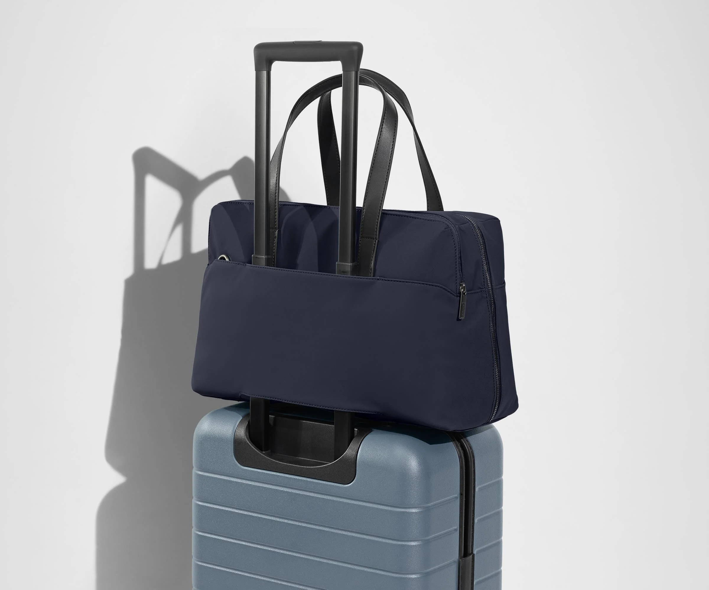 The Everywhere Bag secured to an Away suitcase by its trolley sleeve