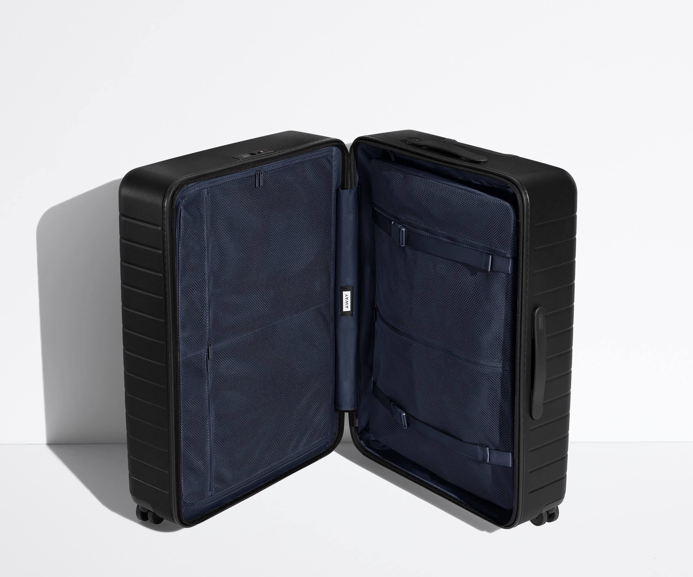 The Medium suitcase in Jet Black shown open in an upright position to show interior organization and compression system