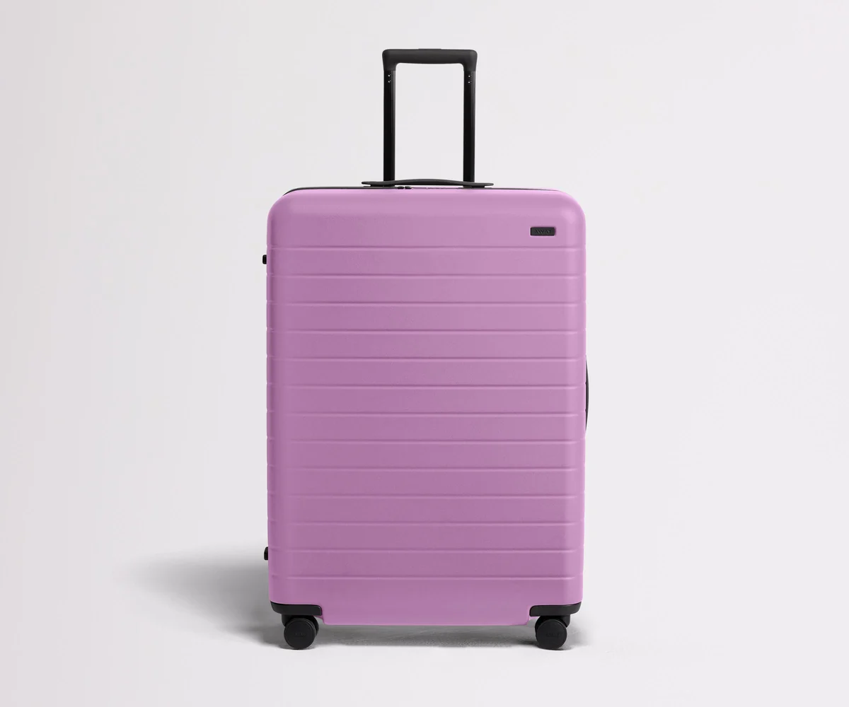 Front product view of The Large suitcase in Taffy Purple with raised handle