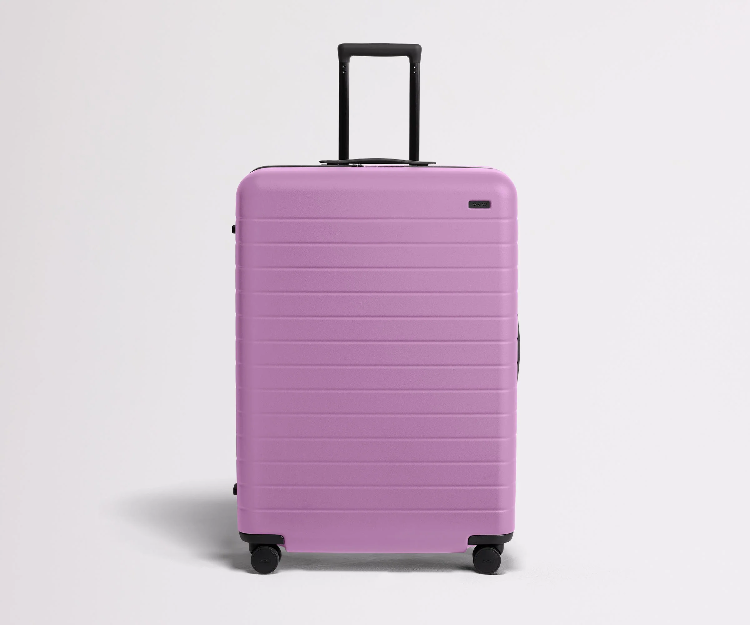Front product view of The Large suitcase in Taffy Purple with raised handle