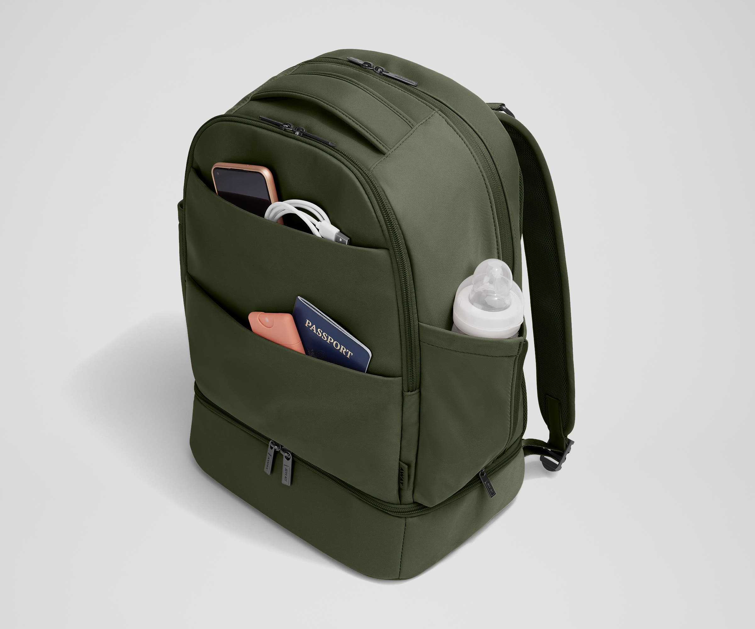 Exterior front pockets packed with travel essentials like a passport and phone, and the exterior bottle pocket packed with a milk bottle