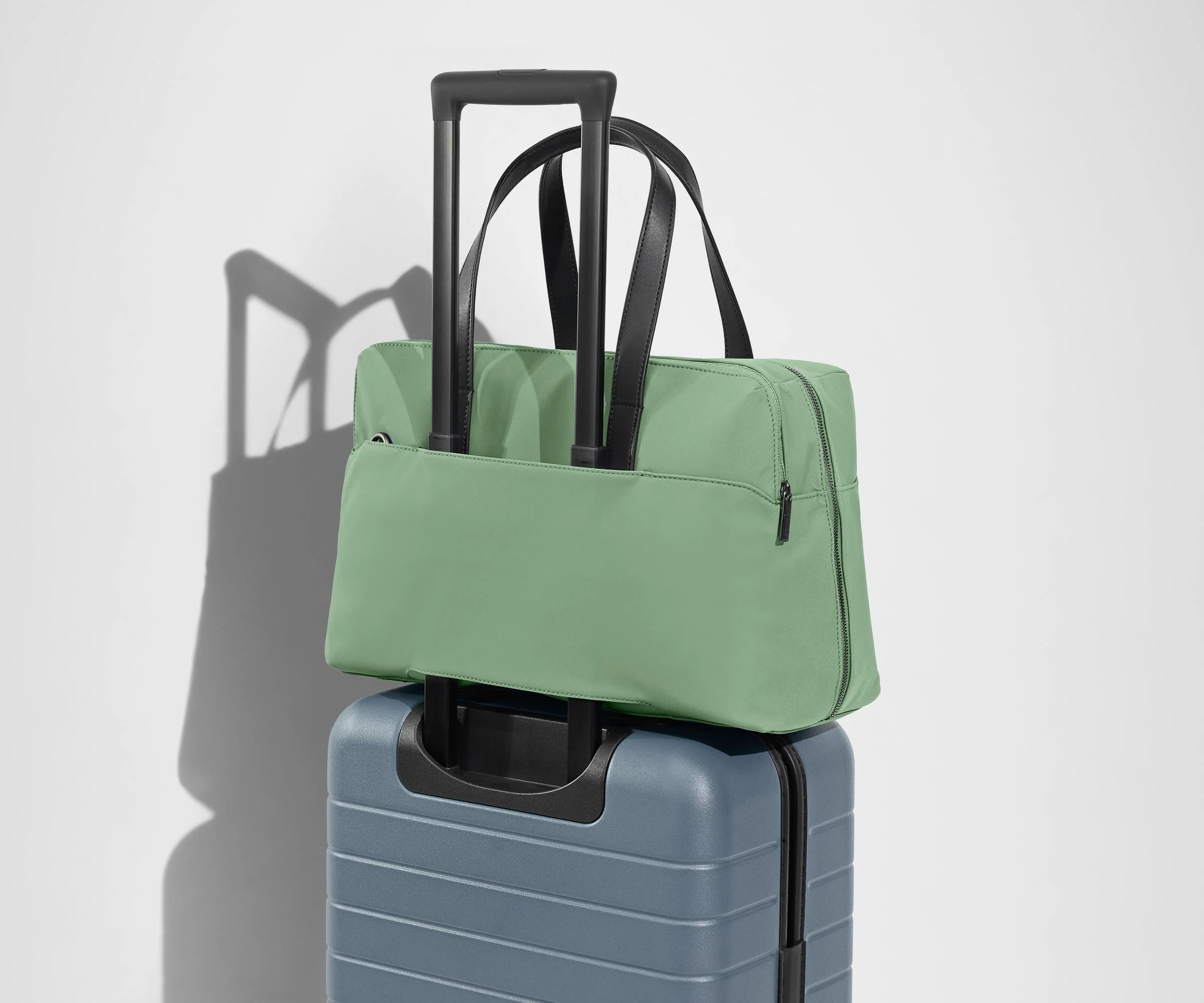 The Everywhere Bag secured to an Away suitcase by its trolley sleeve