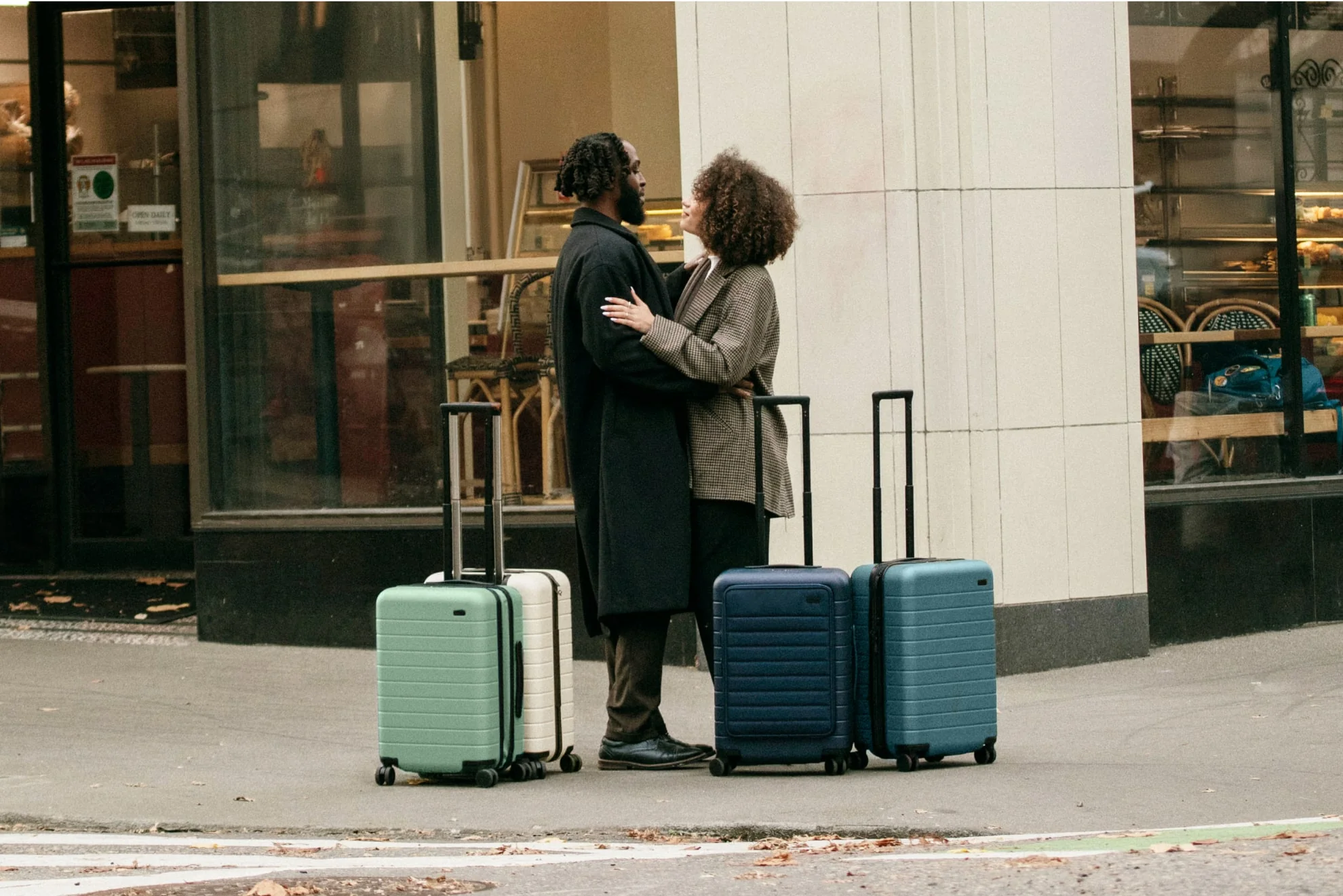 A couple embracing on the streets of Portland surrounded by 4 Away suitcases